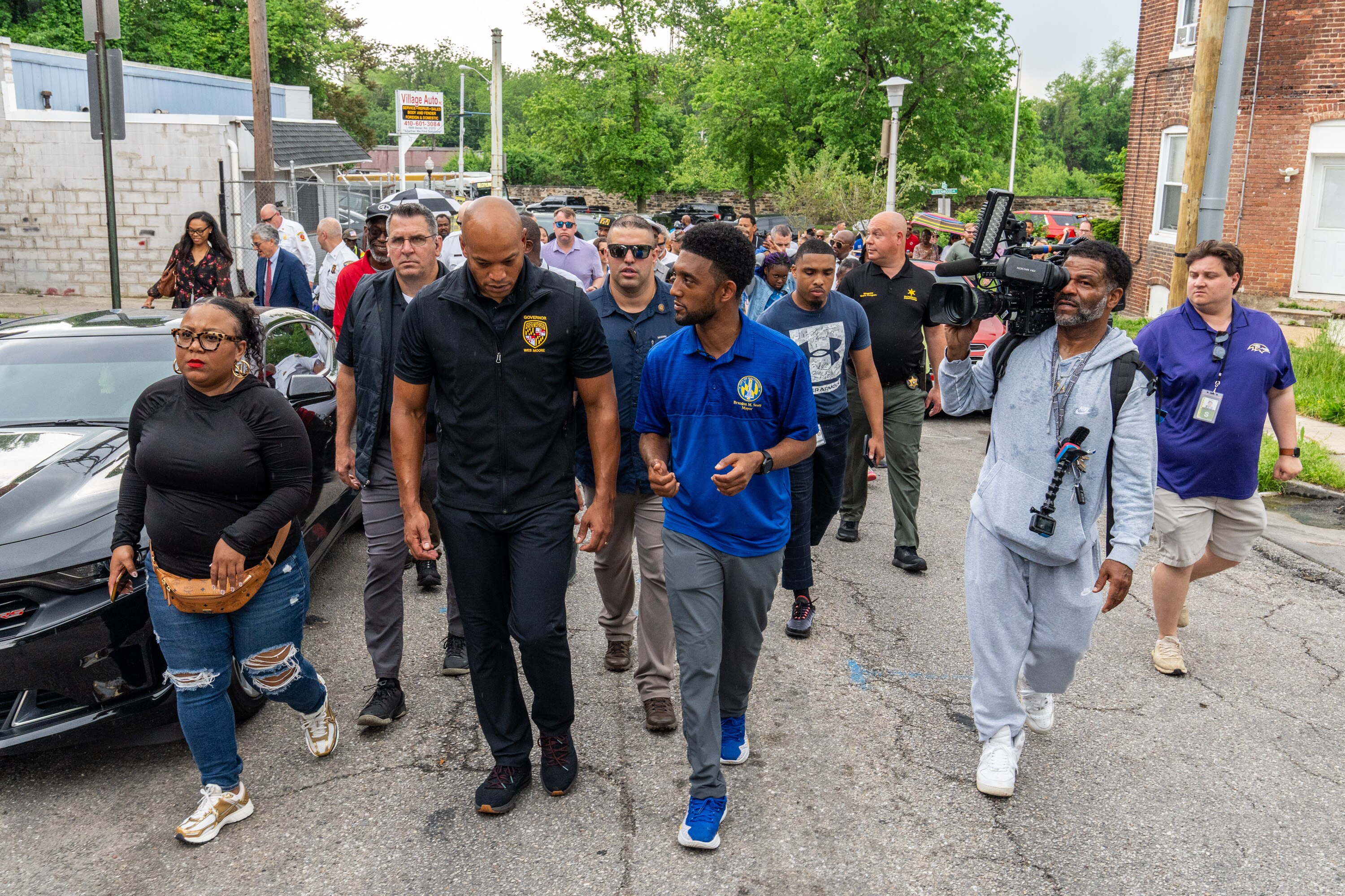 Gov. Wes Moore, center left, and Mayor Brandon Scott, center right, walk through the Four by Four neighborhood on May 7, 2024.