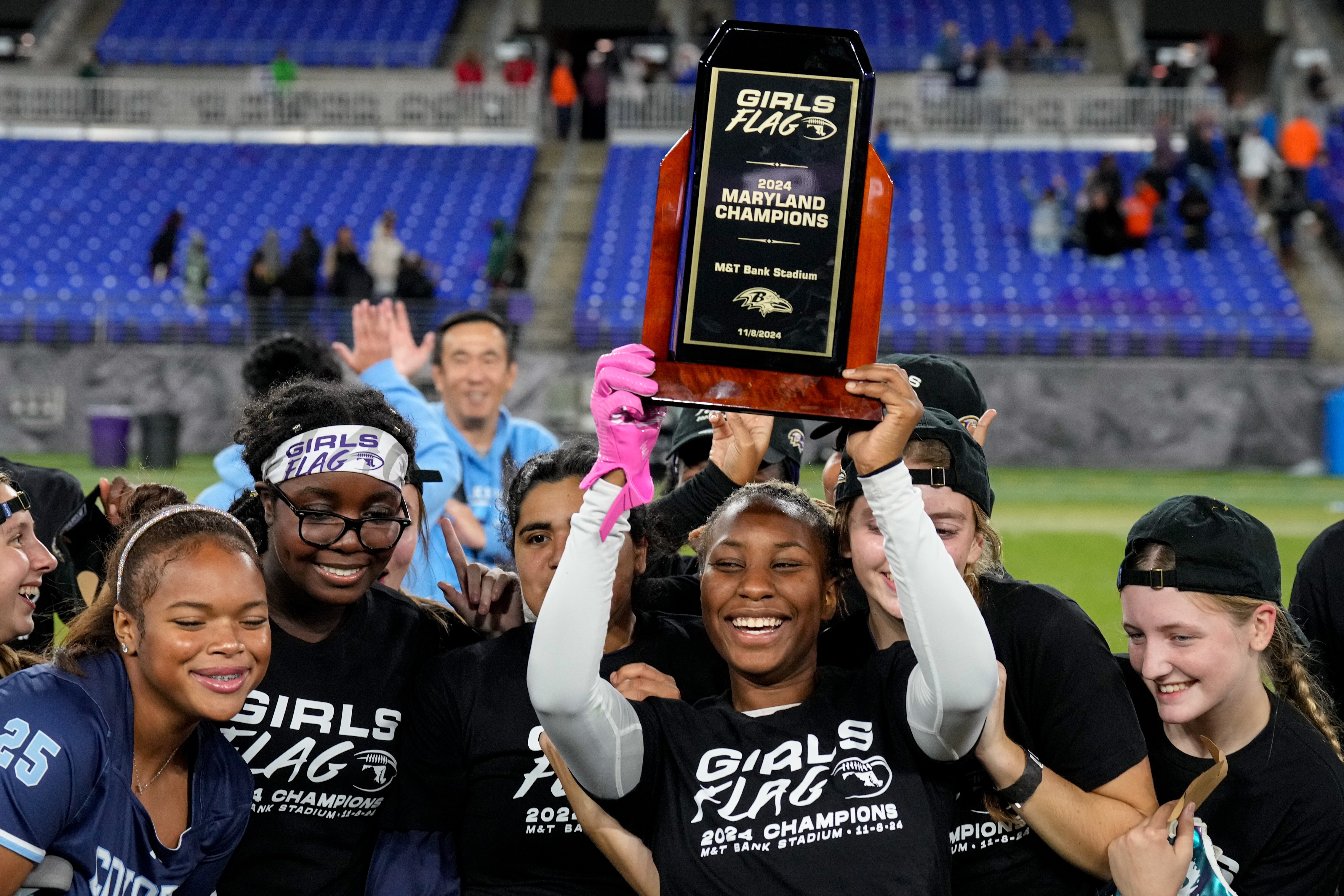 Clarksburg’s Logan Edwards (9) raises the trophy in the air with her teammates after winning the 2024 Maryland High School Girls Flag Football Championship.
