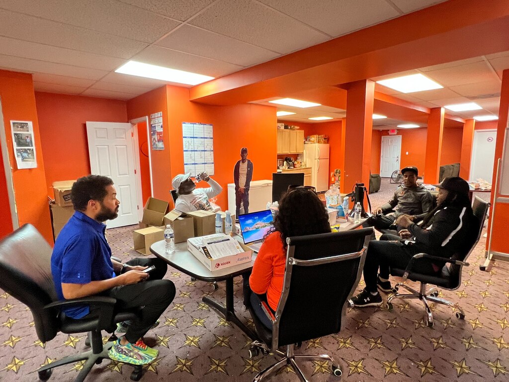 From left to right, Rick Leandry, of the Mayor's Office of Neighborhood Engagement and Safety, sits with Terry "Uncle T" Williams and members of Safe Streets in their Monument Street office, discussing ways they can bring services to the area around North Rose Street following a quadruple shooting.