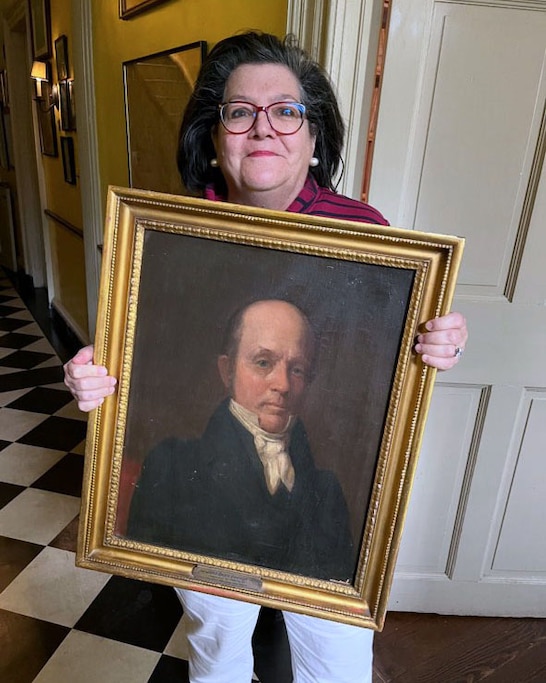 Meg Fairfax Fielding holds an 1844 portrait of Dr. John Beale Davidge, founder and first dean of the University of Maryland School of Medicine.