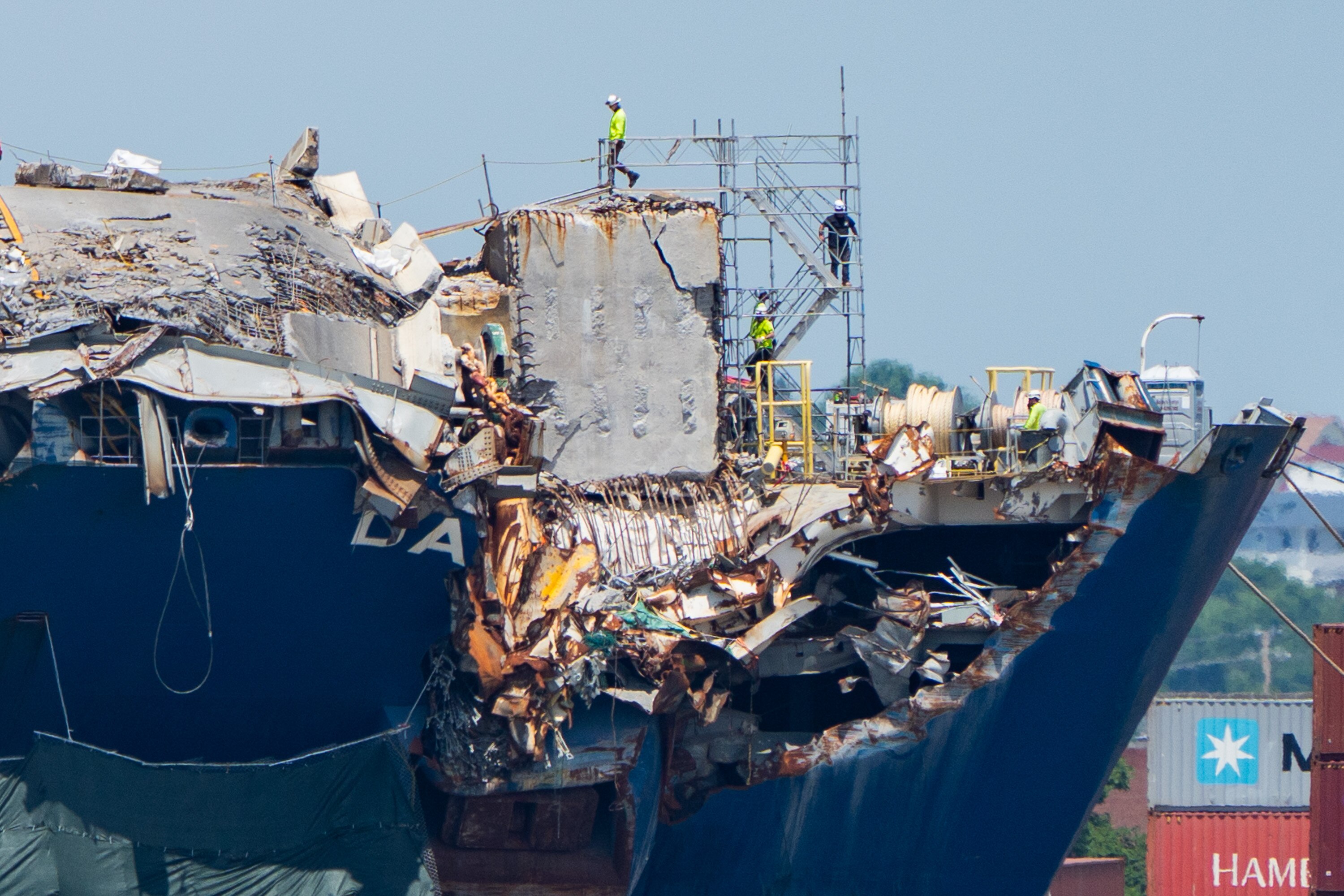 Workers walk along the destroyed bow of the Dali in May 2024.