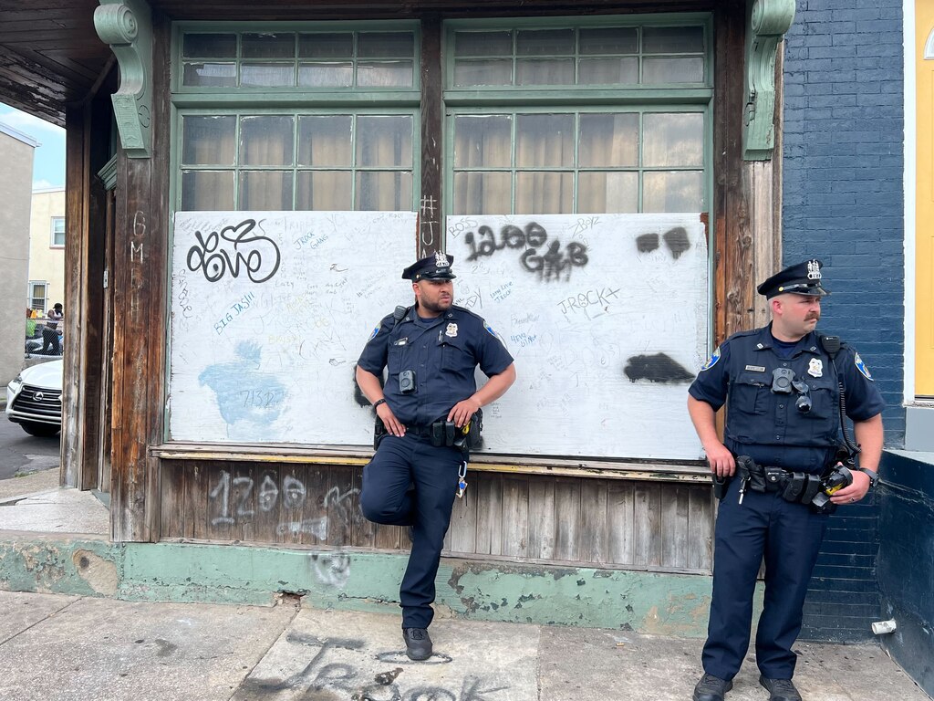 Two Eastern District patrol officers post up at Greenmount Avenue and Mura Street as an array of city officials assemble to thwart a youth party that has rankled residents of Mura Street.