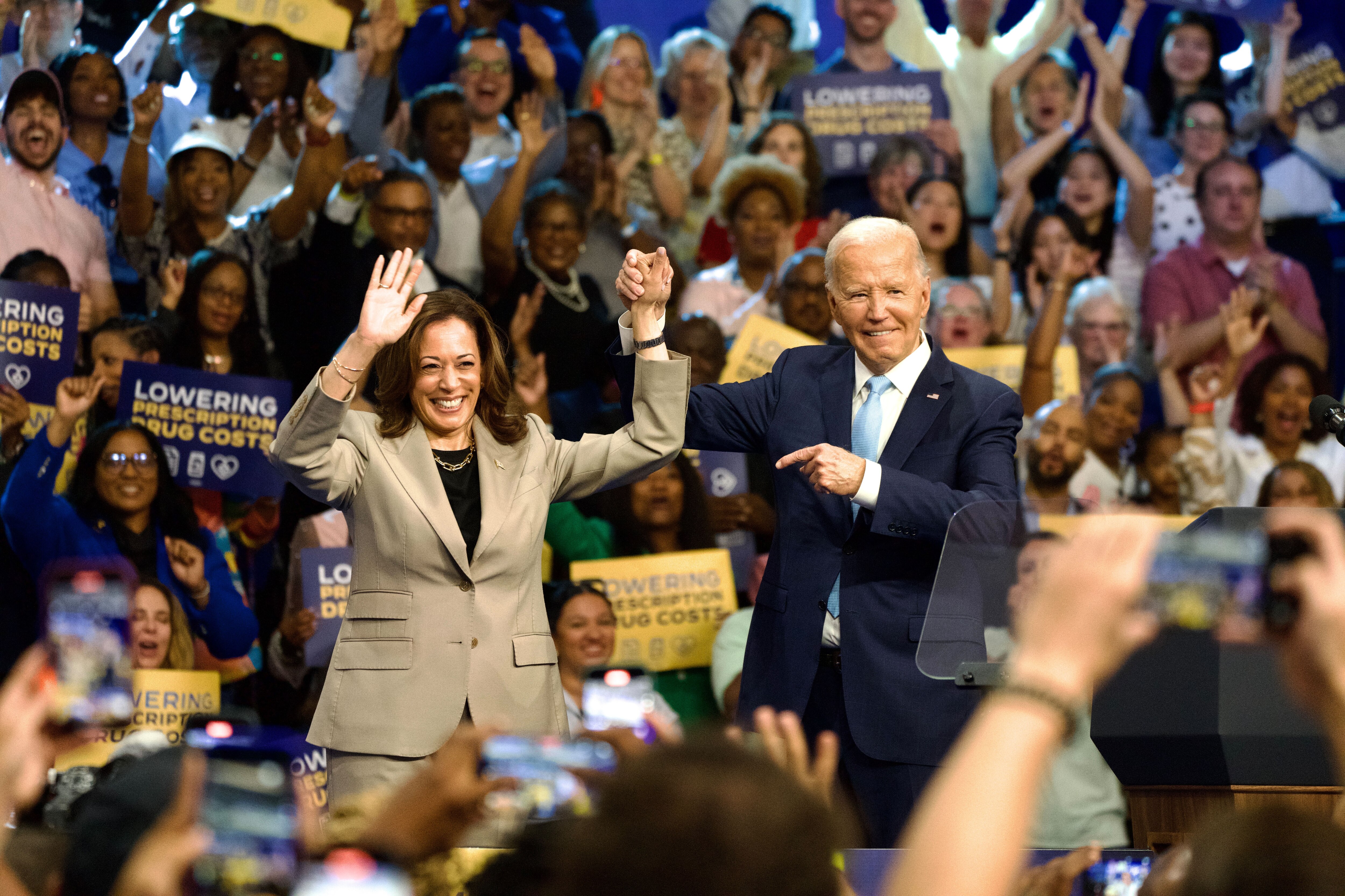 President Joe Biden and Vice President Kamala Harris raise their hands together after delivering remarks on prescription drug costs at Prince George's Community College on Thursday.