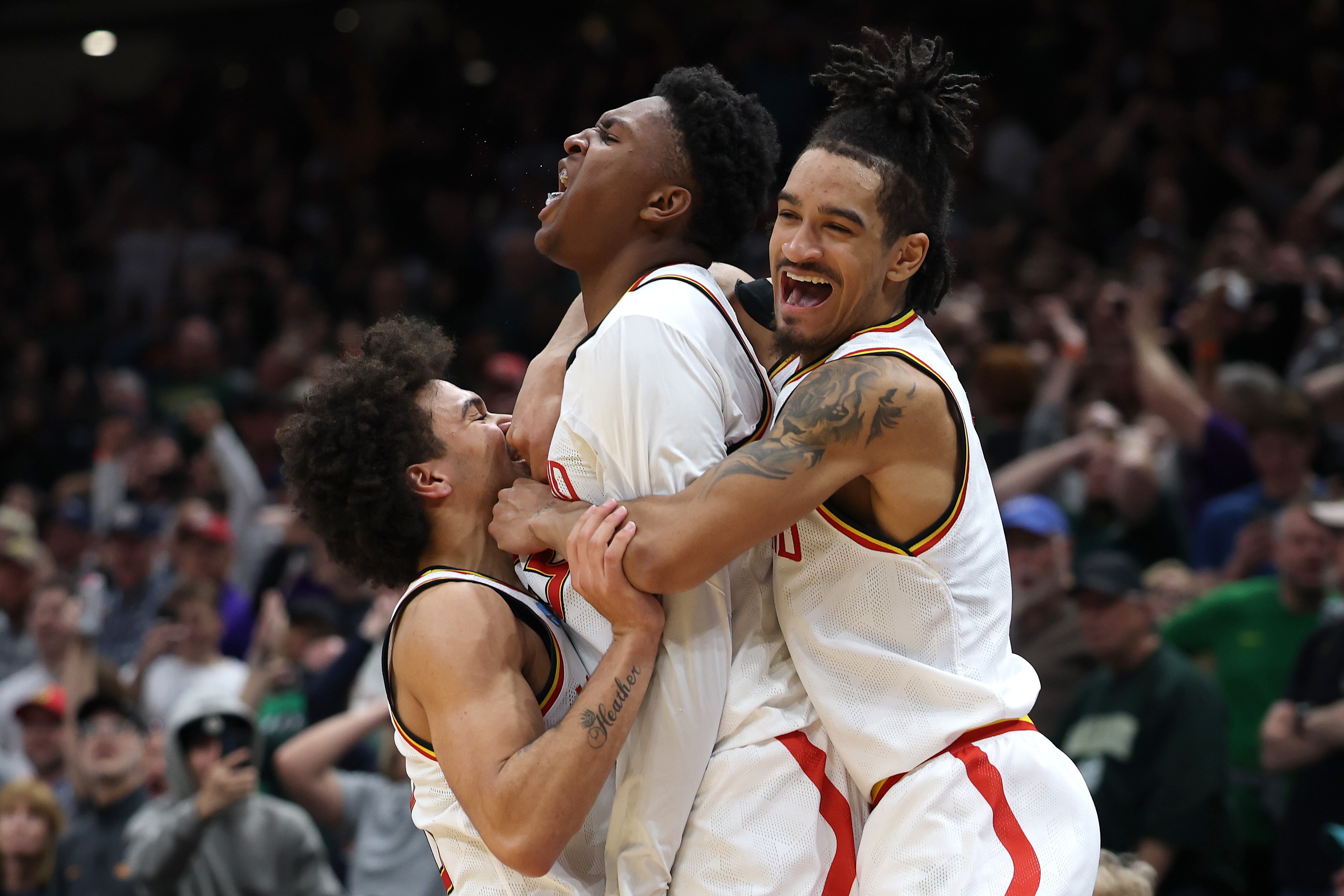 Teammates sandwich Derik Queen after his game-winning shot against Colorado State on Sunday in Seattle.