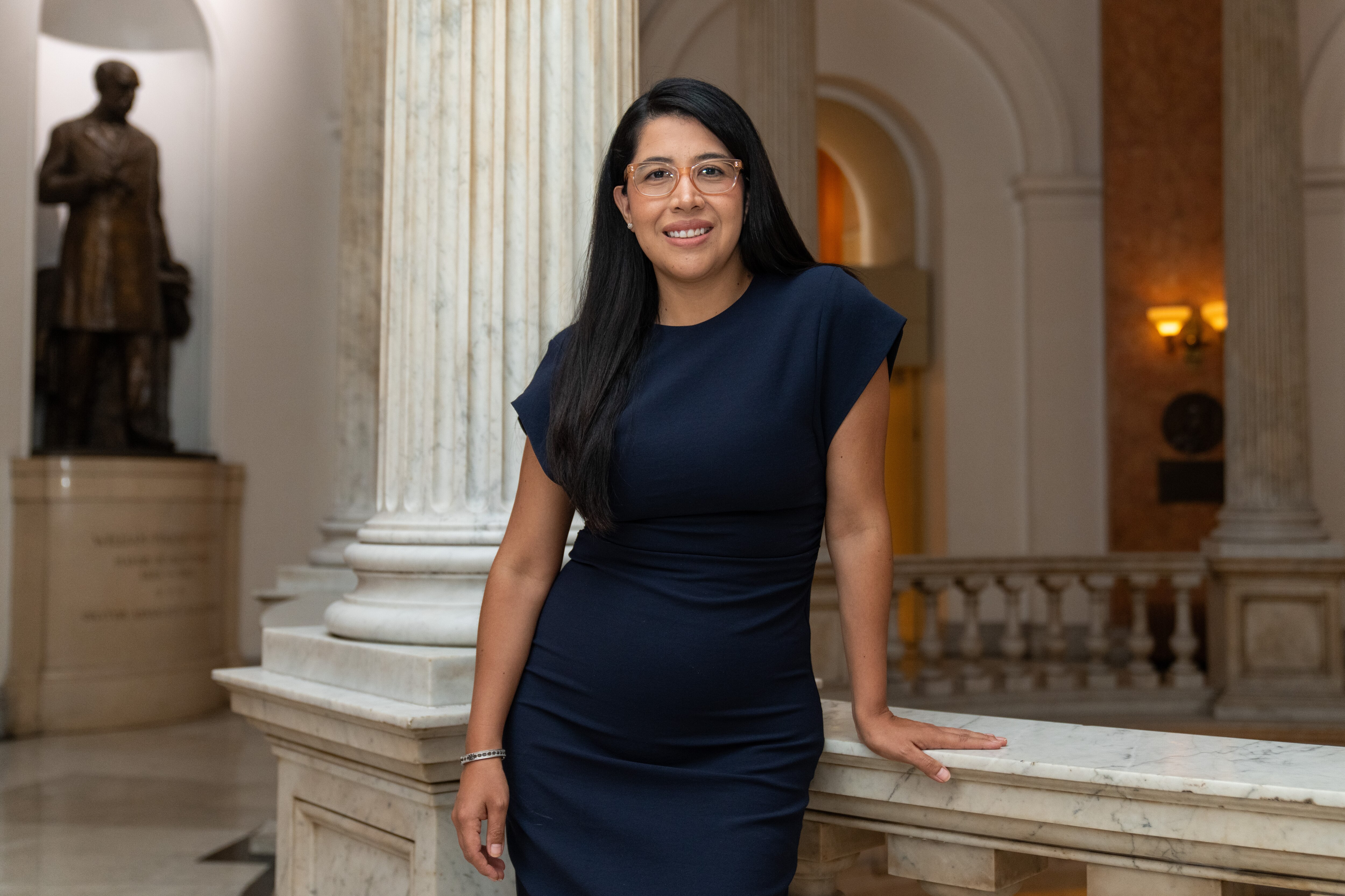 Catalina Rodriguez Lima poses for a portrait in the City Hall rotunda with her left hand on the rail.