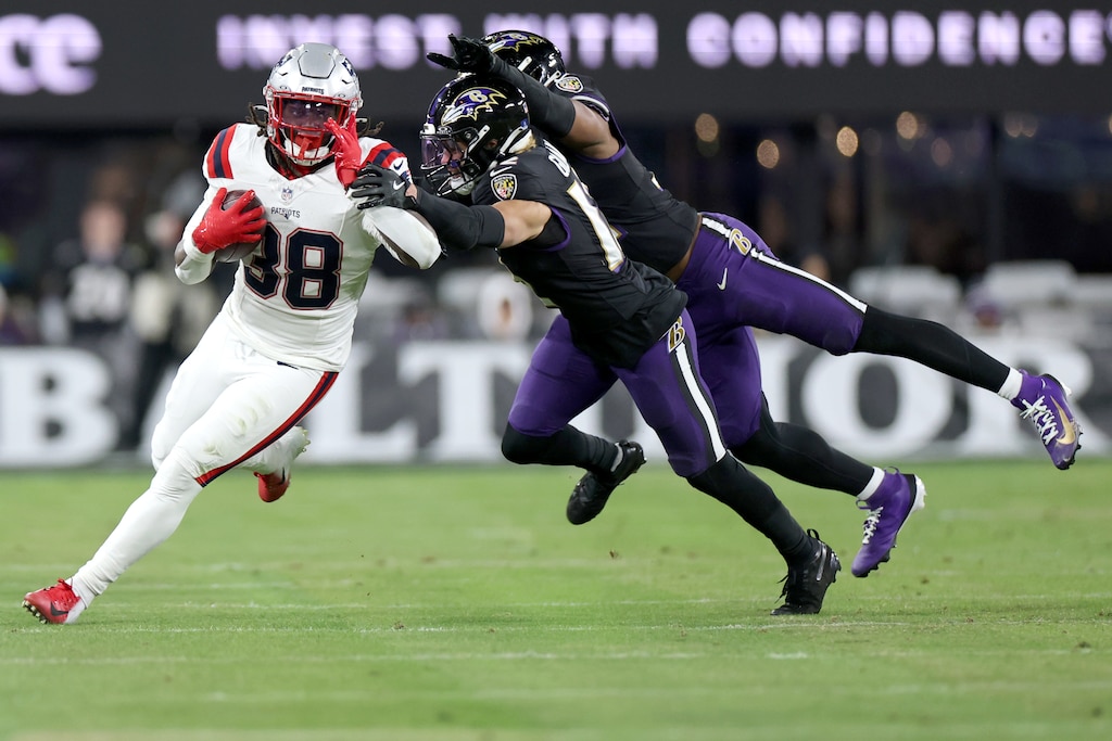 BALTIMORE, MARYLAND - DECEMBER 21: Rhamondre Stevenson #38 of the New England Patriots carries the ball after a reception as Alohi Gilman #12 and Trenton Simpson #32 of the Baltimore Ravens attempt a tackle during the third quarter at M&T Bank Stadium on December 21, 2025 in Baltimore, Maryland.