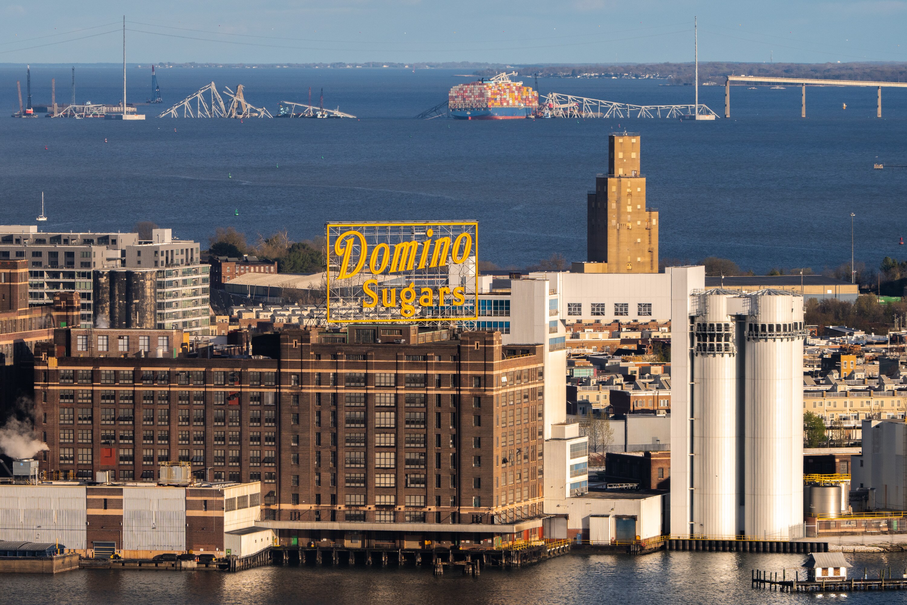 The wreckage of the Key Bridge collapse, with the Domino Sugar factory in the foreground, is seen from the Baltimore World Trade Center on Saturday, April 6, 2024.