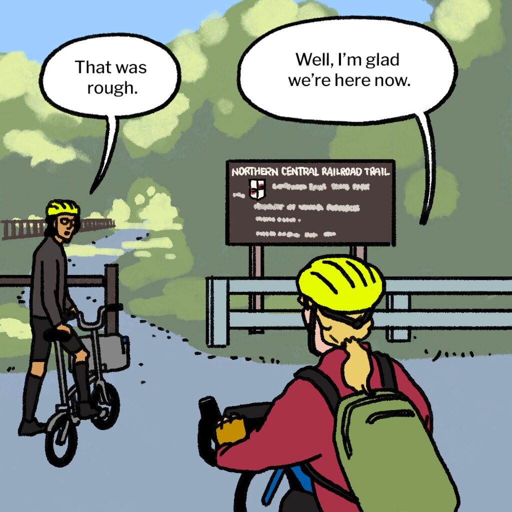 Illustration of man and woman, seen from behind, on bikes in parking lot in front of the beginning of a trail that leads into the forest. A brown sign says "Northern Central Railroad Trail." Man looks back at woman and says: "That was rough." Woman says: "Well, I'm glad we're here now."