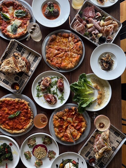 A spread of food from Raffy's on 36th, including their tomato pie, pepperoni pizza, margherita pizza, meatball sandwich, and many appetizers.