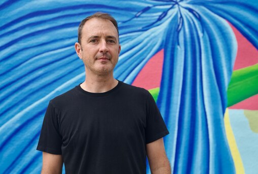 Local artist Andy Dahl stands in front of the mural he painted on the home of Charles Foster, which was shown to the public for the first time on July 18, 2024. The mural took Dahl about a month to finish.