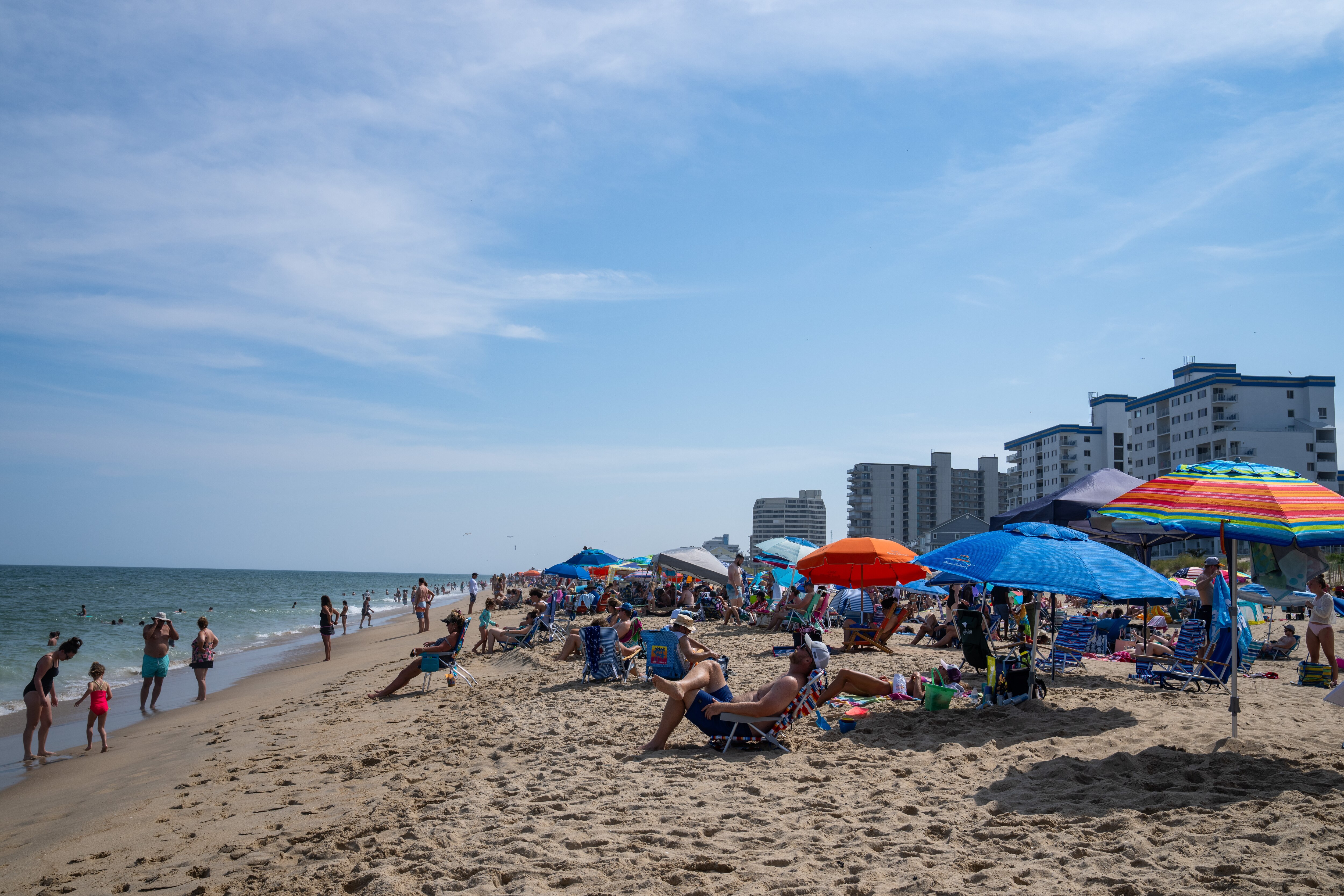 People go in the water and lounge under umbrellas at Ocean City Beach.