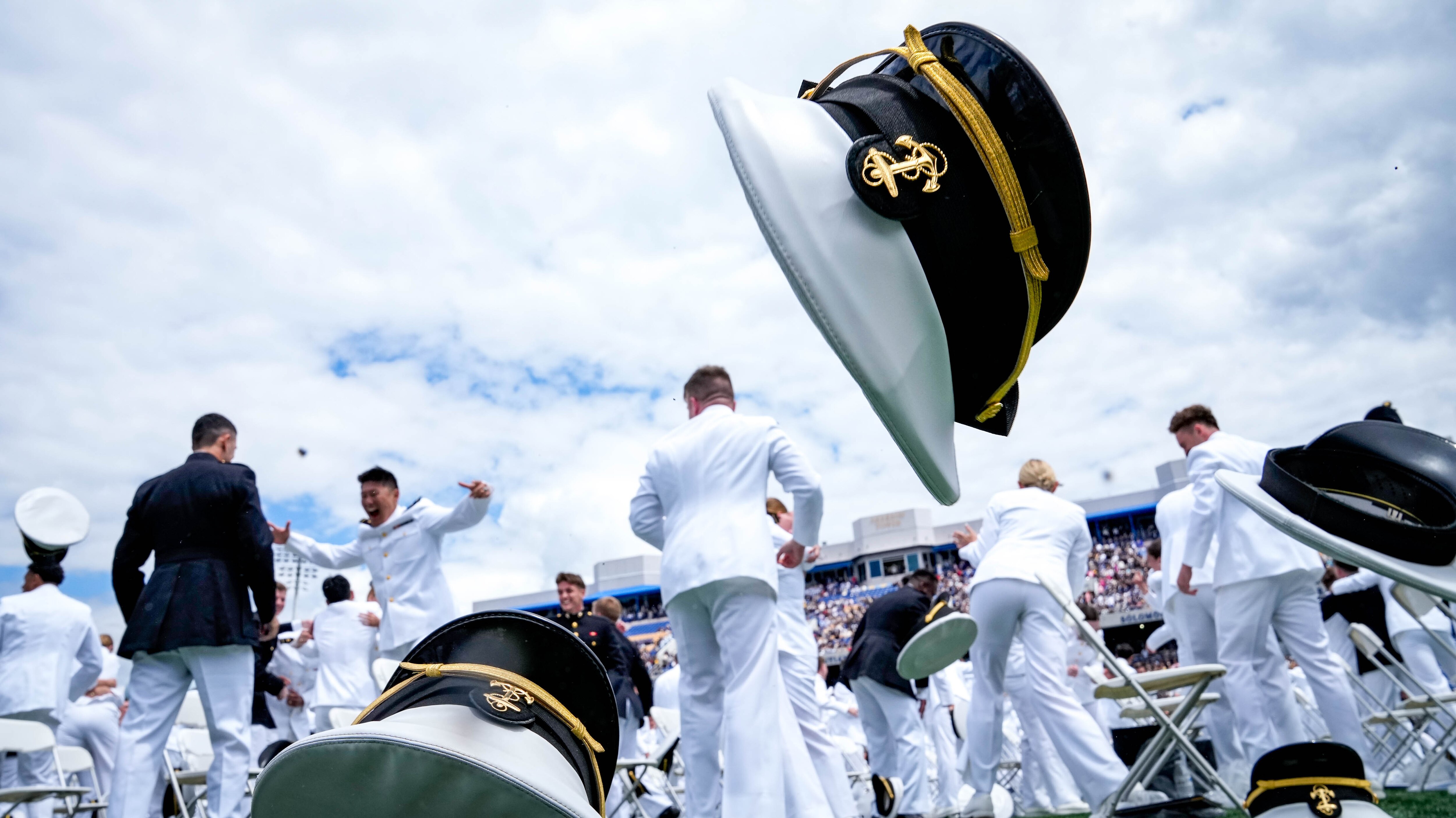 Graduating midshipmen in the U.S. Naval Academy Class of 2025 toss their hats in the air to celebrate graduating. 