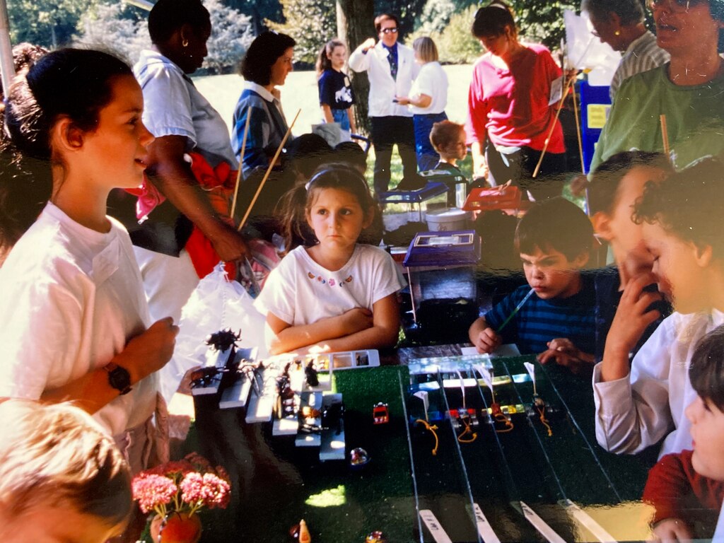 Kelly MacBride-Gill, left, stands near a cockroach race as a child. The race was organized by her father, Stanton Gill, pictured in the far back center in white.
