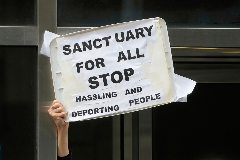 A person holds up a sign during a news conference and rally by immigrant justice organizations and advocates protesting ICE arrests in San Francisco