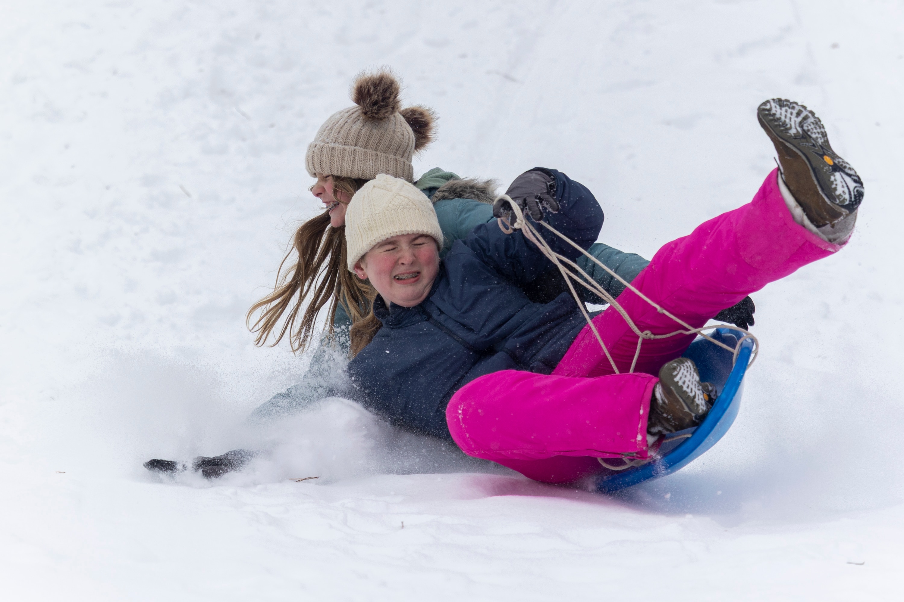 Cynthia Ferguson, left, and Joni Kayne sled down a hill on Sunday, Jan. 25, 2026, during a snowstorm  in Silver Spring, Md. at Pinecrest Park.