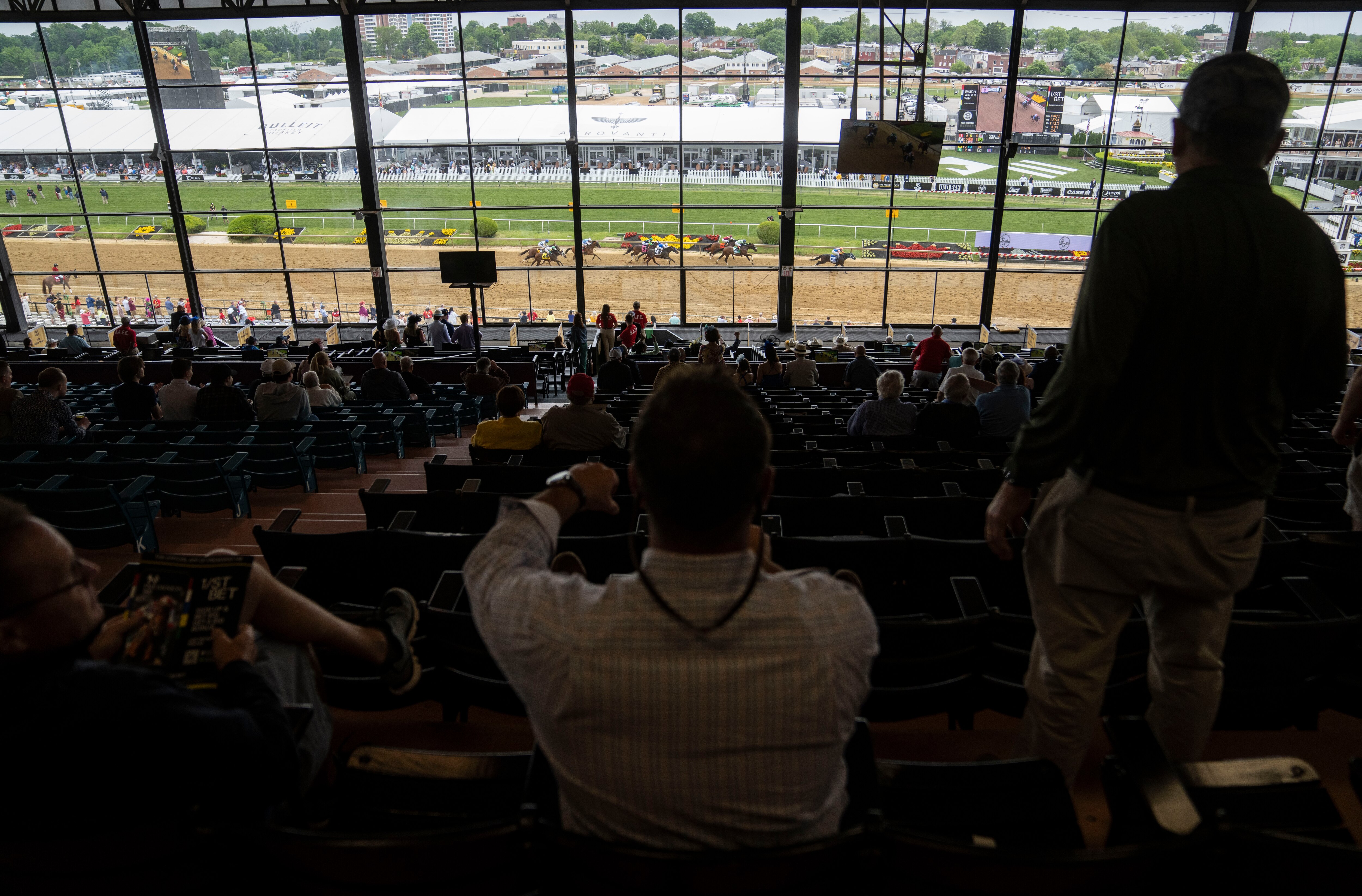 Fans watch horses dash toward the finish line at Pimlico Race Course in May.