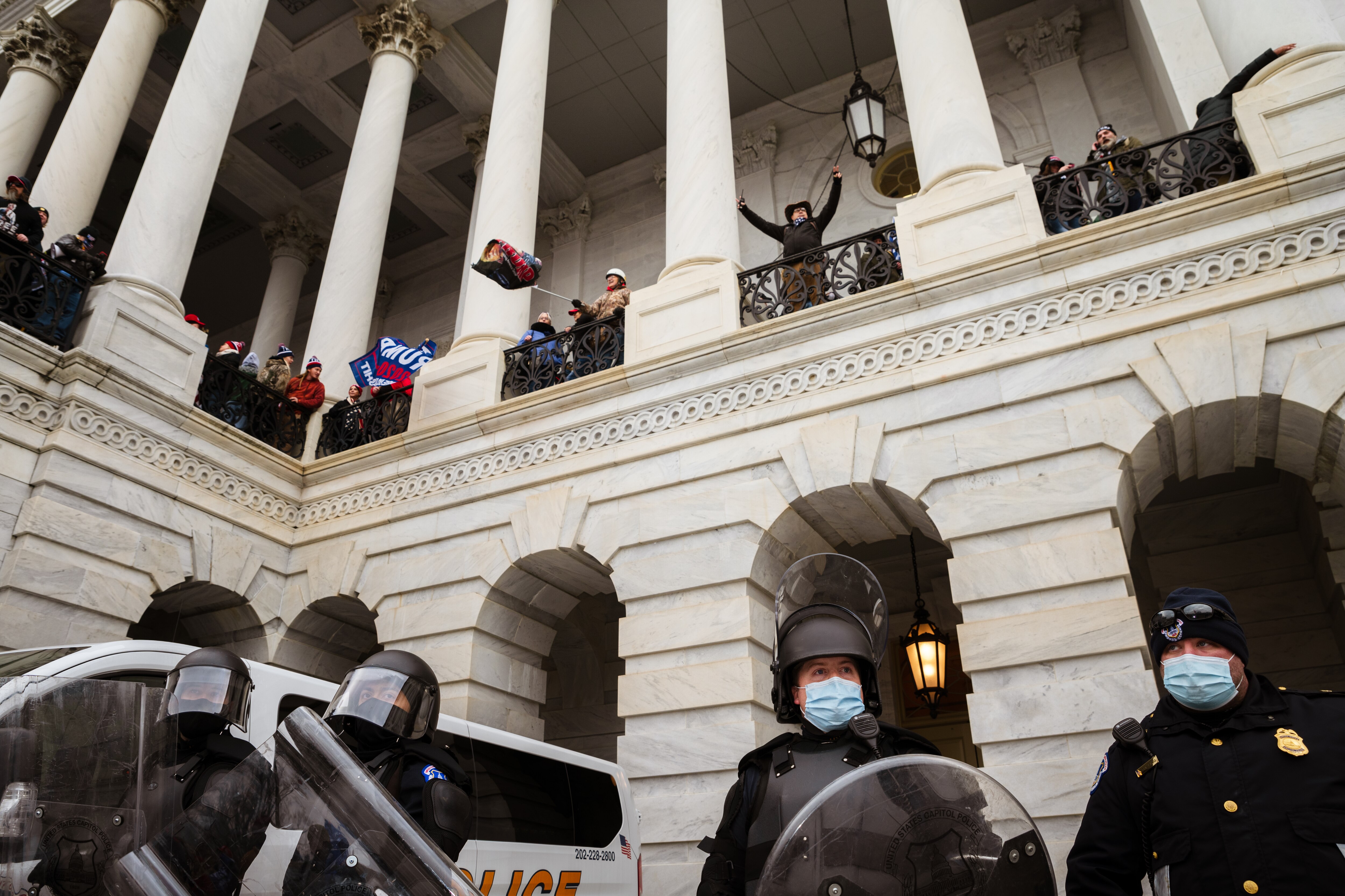 WASHINGTON, DC - JANUARY 06: A group of pro-Trump protesters wave flags from a platform above a group of Capitol Police after storming the Capitol Building on January 6, 2021 in Washington, DC. A pro-Trump mob stormed the Capitol, breaking windows and clashing with police officers. Trump supporters gathered in the nation's capital today to protest the ratification of President-elect Joe Biden's Electoral College victory over President Trump in the 2020 election.