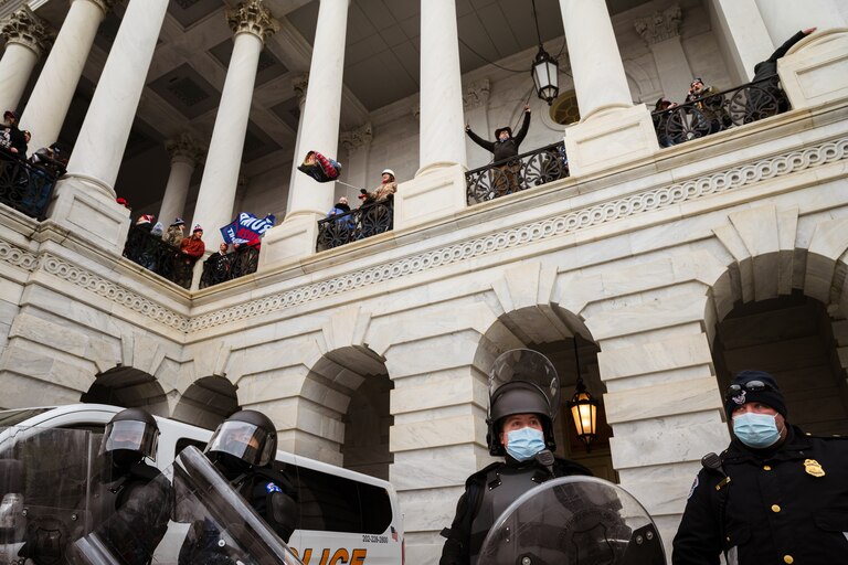 WASHINGTON, DC - JANUARY 06: A group of pro-Trump protesters wave flags from a platform above a group of Capitol Police after storming the Capitol Building on January 6, 2021 in Washington, DC. A pro-Trump mob stormed the Capitol, breaking windows and clashing with police officers. Trump supporters gathered in the nation's capital today to protest the ratification of President-elect Joe Biden's Electoral College victory over President Trump in the 2020 election.