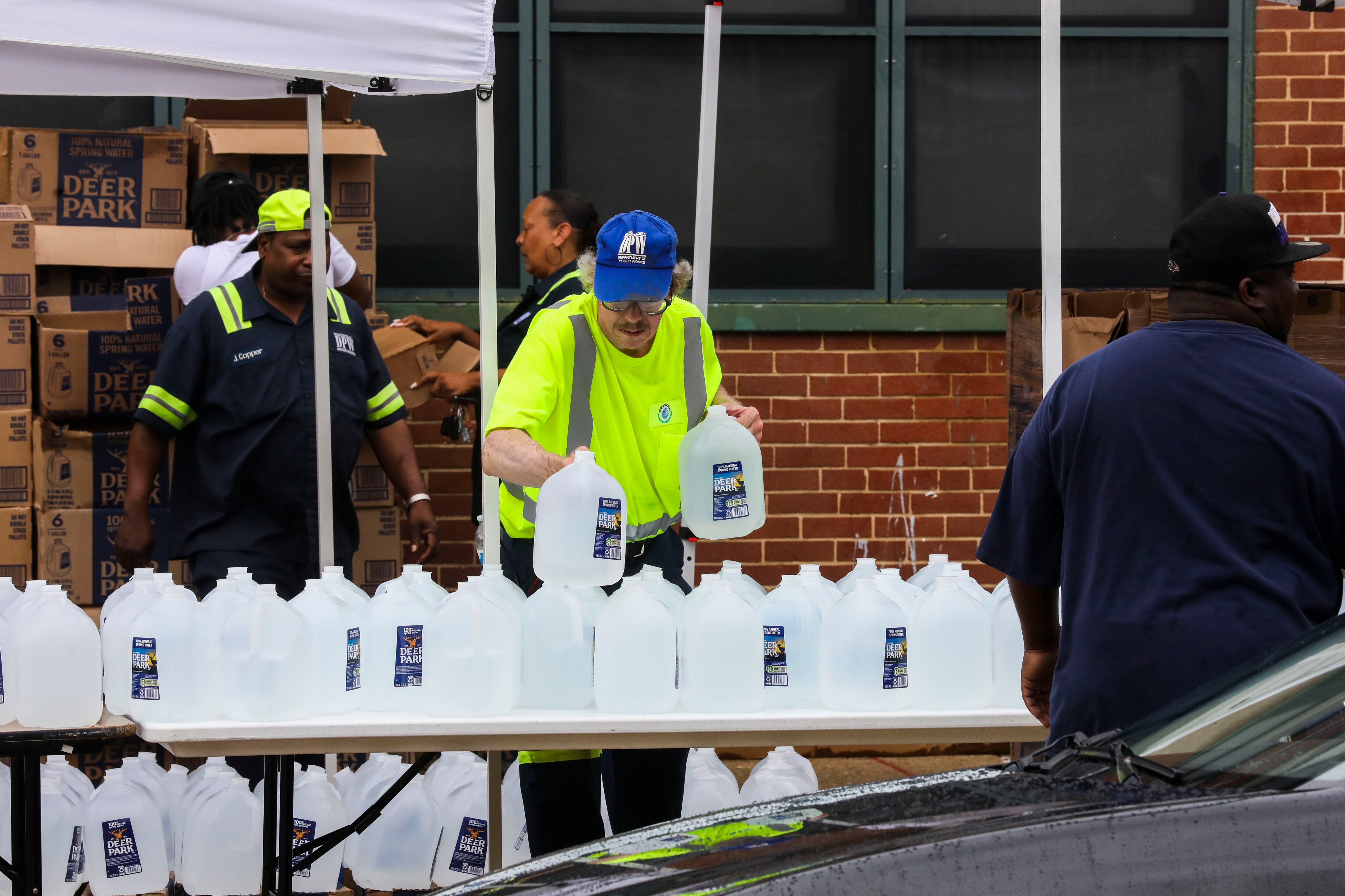 Baltimore Department of Public Works employees hand out water in Harlem Park after the city issued a boil advisory. Baltimore’s public works department first noted E. coli and coliform through routine testing on Friday.