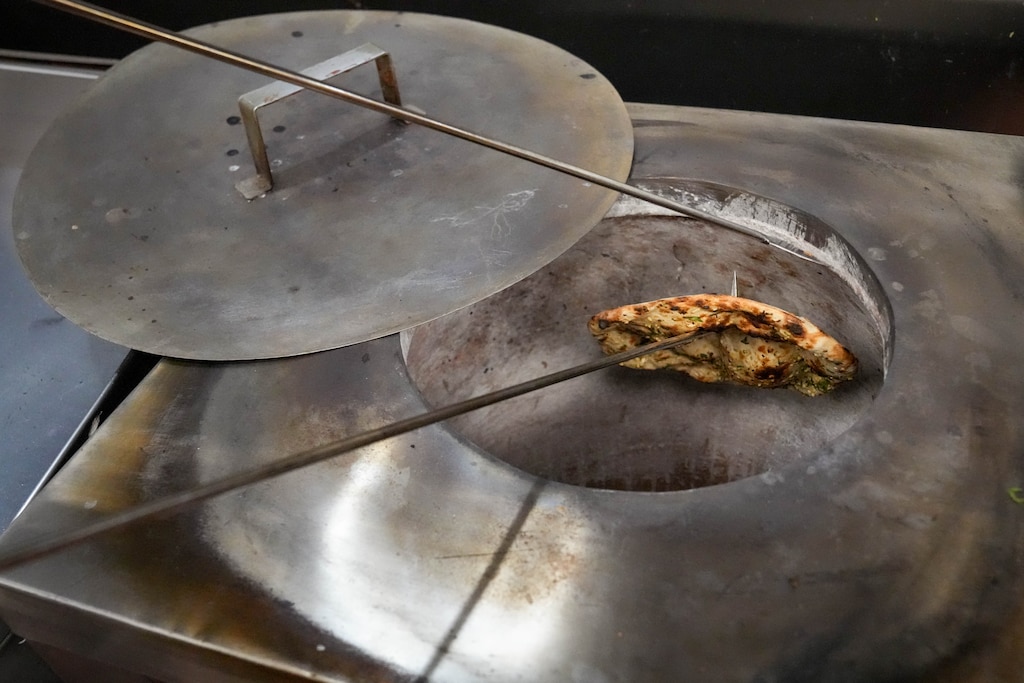 Head chef Gurnek Bassi removes garlic naan from the oven at India Tandoor, a small Indian restaurant in the back of a convenience store in the Remington neighborhood of Baltimore, Md. on Wednesday, March 19, 2025.