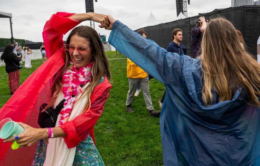 Two friends dance together in the rain at Infield Fest during Preakness at Pimlico on May 18, 2024.