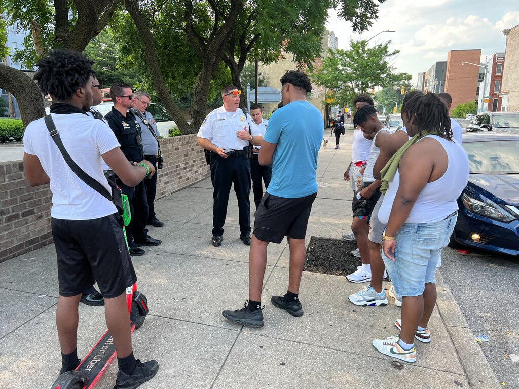 Eastern District Maj. Guy Thacker, middle, speaks to a group of young men frustrated that the city blocked their efforts to throw a party on Mura Street. Officials spent a week trying to thwart the party based on concerns from neighbors.