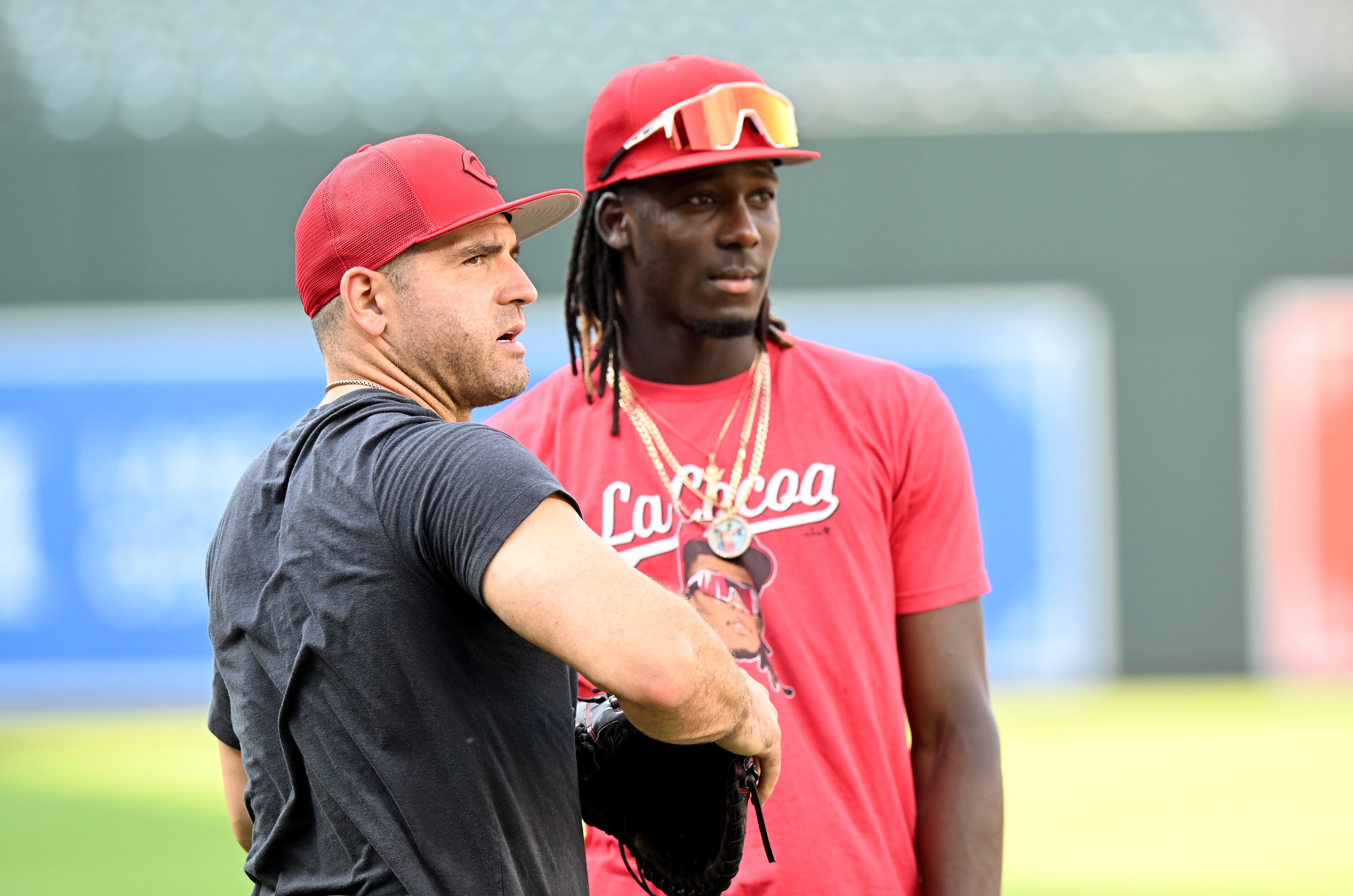 Joey Votto, No. 19 (L), and Elly De La Cruz, No. 44, of the Cincinnati Reds talk before the game against the Baltimore Orioles at Oriole Park at Camden Yards on June 26, 2023 in Baltimore, Maryland.