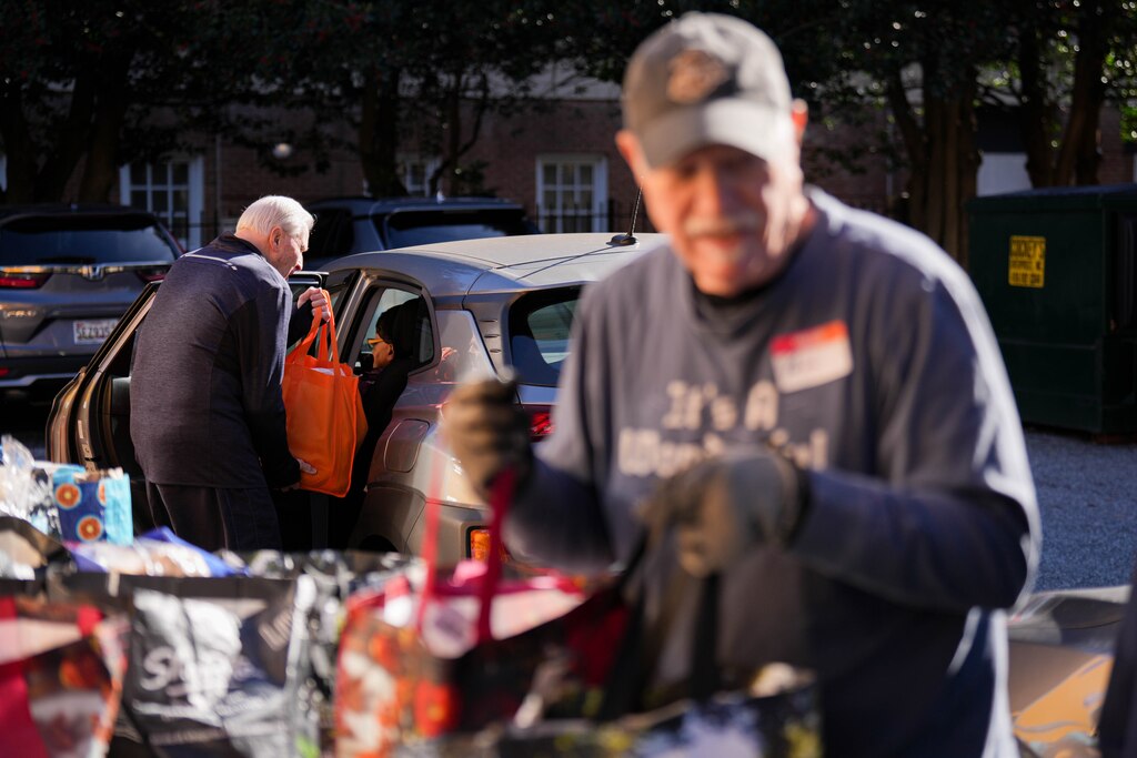 Gus Bengel, left, puts food into a woman’s backseat as Paul Sullivan prepares to do the same for another recipient during a Thanksgiving holiday meal giveaway at Trinity Episcopal Church in Towson, Md., on Monday, November 24, 2025. The Assistance Center of Towson Churches organized the event, which was also held in 2024.