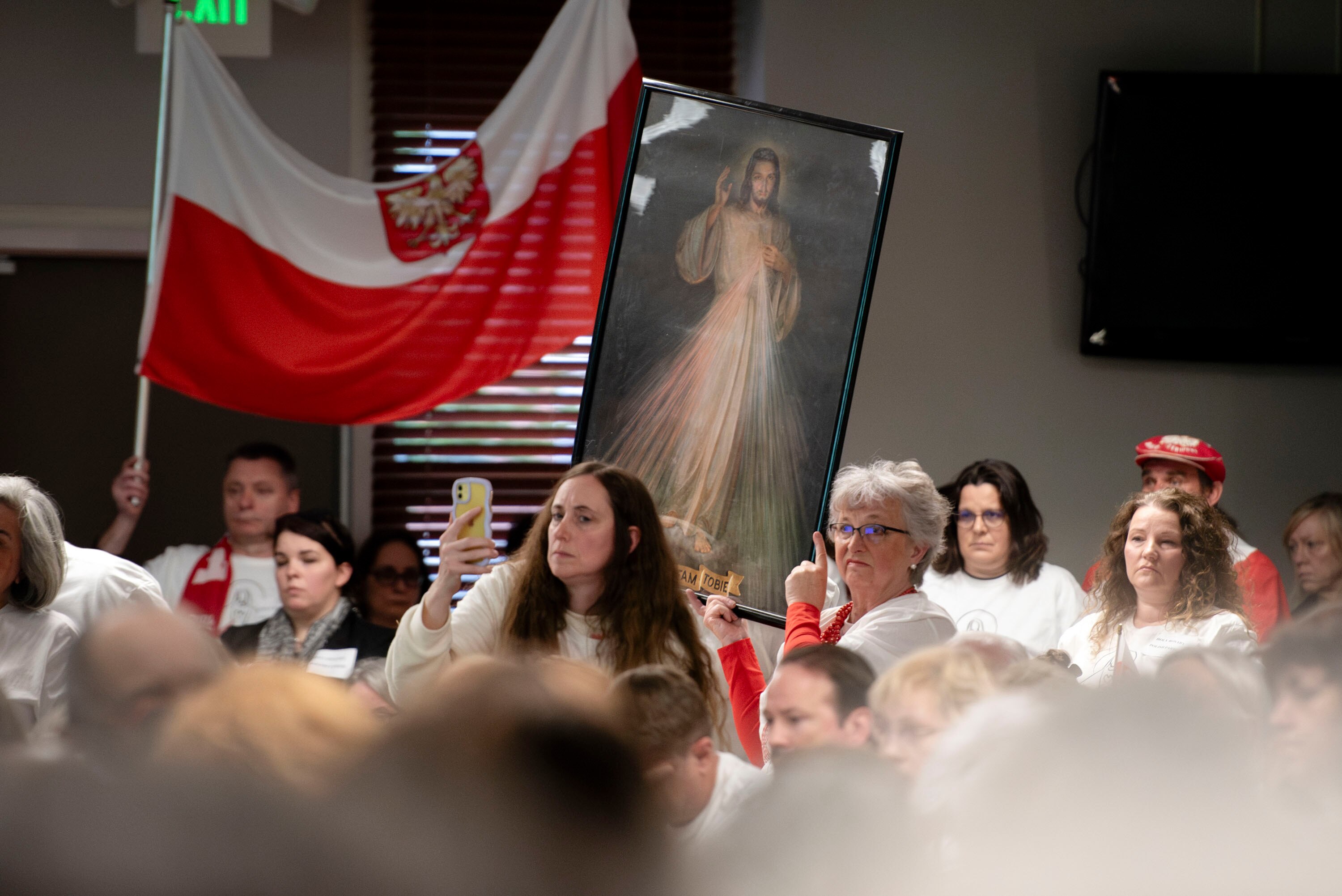 Members of the Holy Rosary Church hold up flags and an image of Jesus during a presentation at Seek the City Night on 4/25/2024 in Baltimore, MD.