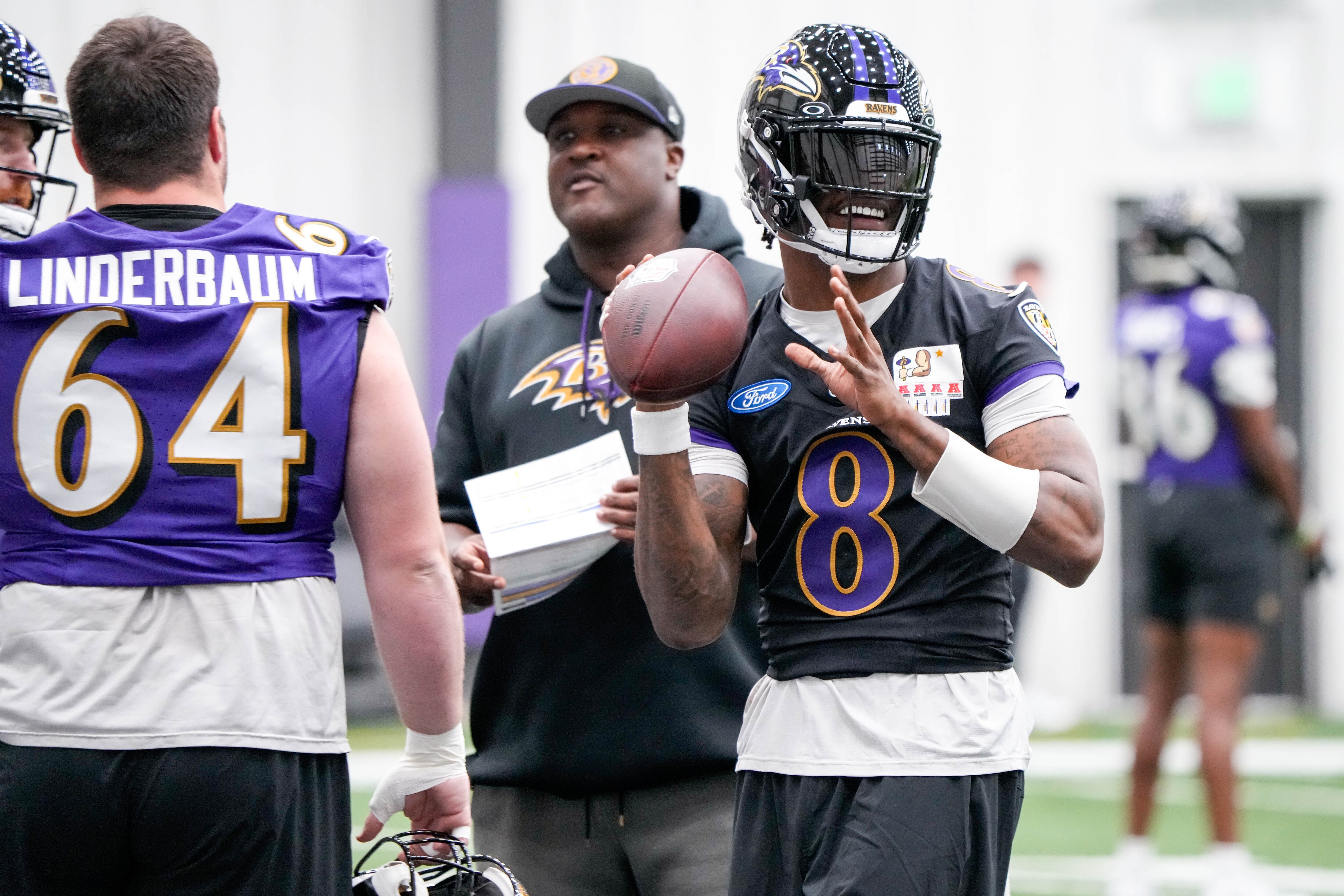 Ravens quarterback Lamar Jackson, right, smiles as he throws a pass during organized team activities at the Under Armour Performance Center on Wednesday.