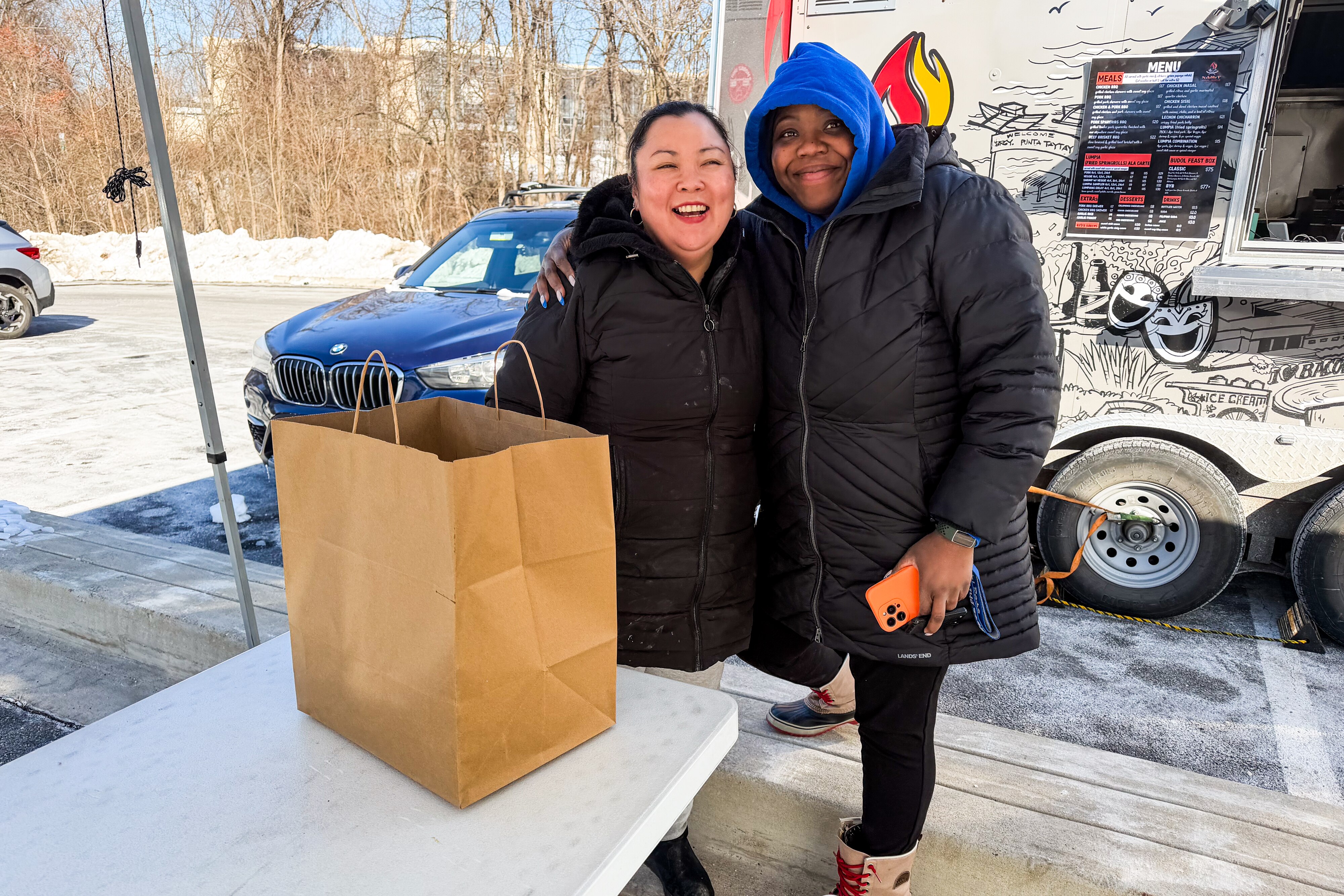 Owner of Namit BBQ Food Truck Maria Tabligan poses with customer Valerie Forrester, who's stocking up on meat skewers as the truck closes until Spring.