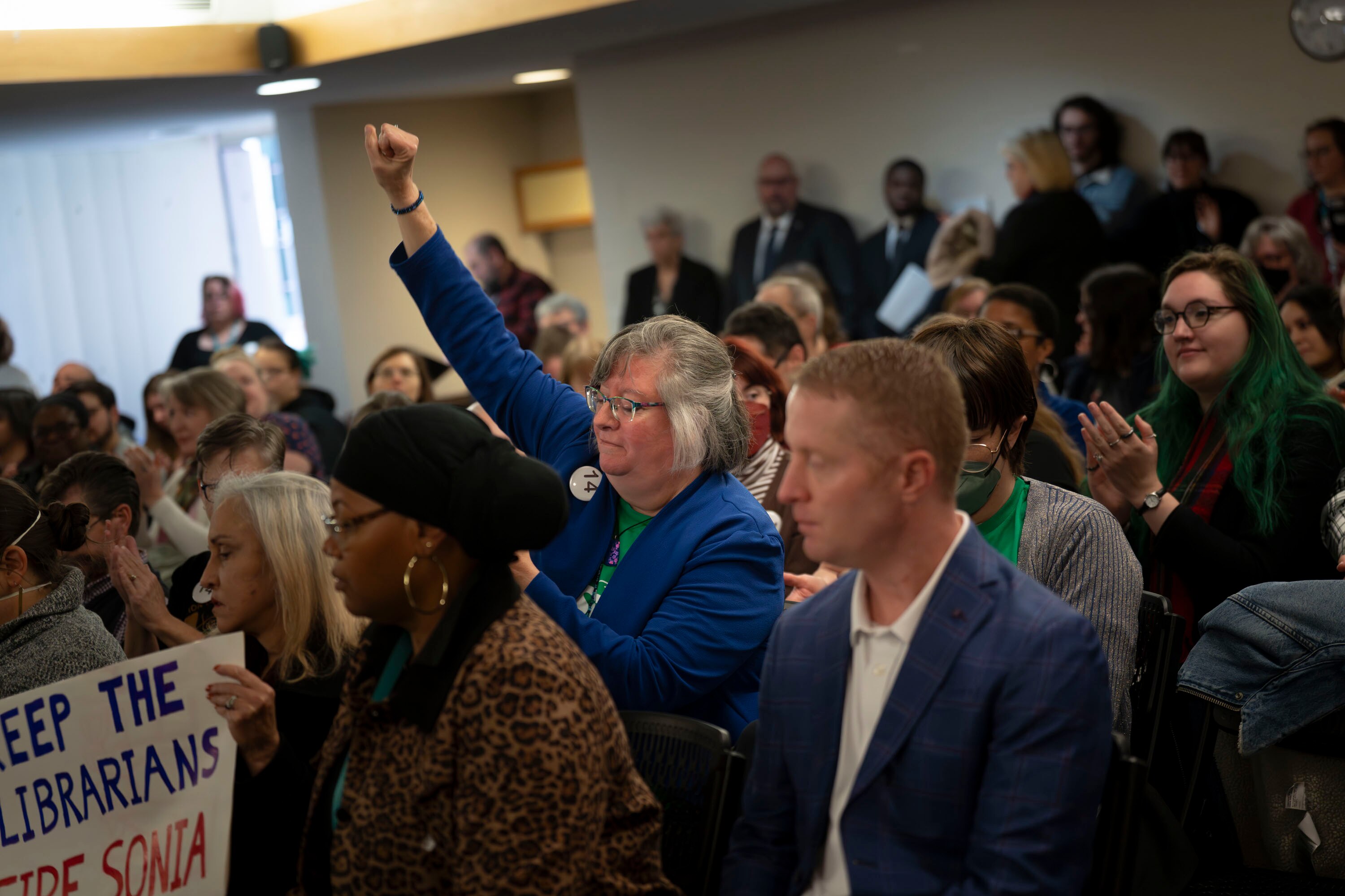 Laura Kellman, a librarian from Anne Arundel County, raises a fist in solidarity as her peers speak out at an emergency meeting to address their grievances last month in Towson. This week, Baltimore County Public Library’s board announced that their part-time librarians’ jobs will be protected.