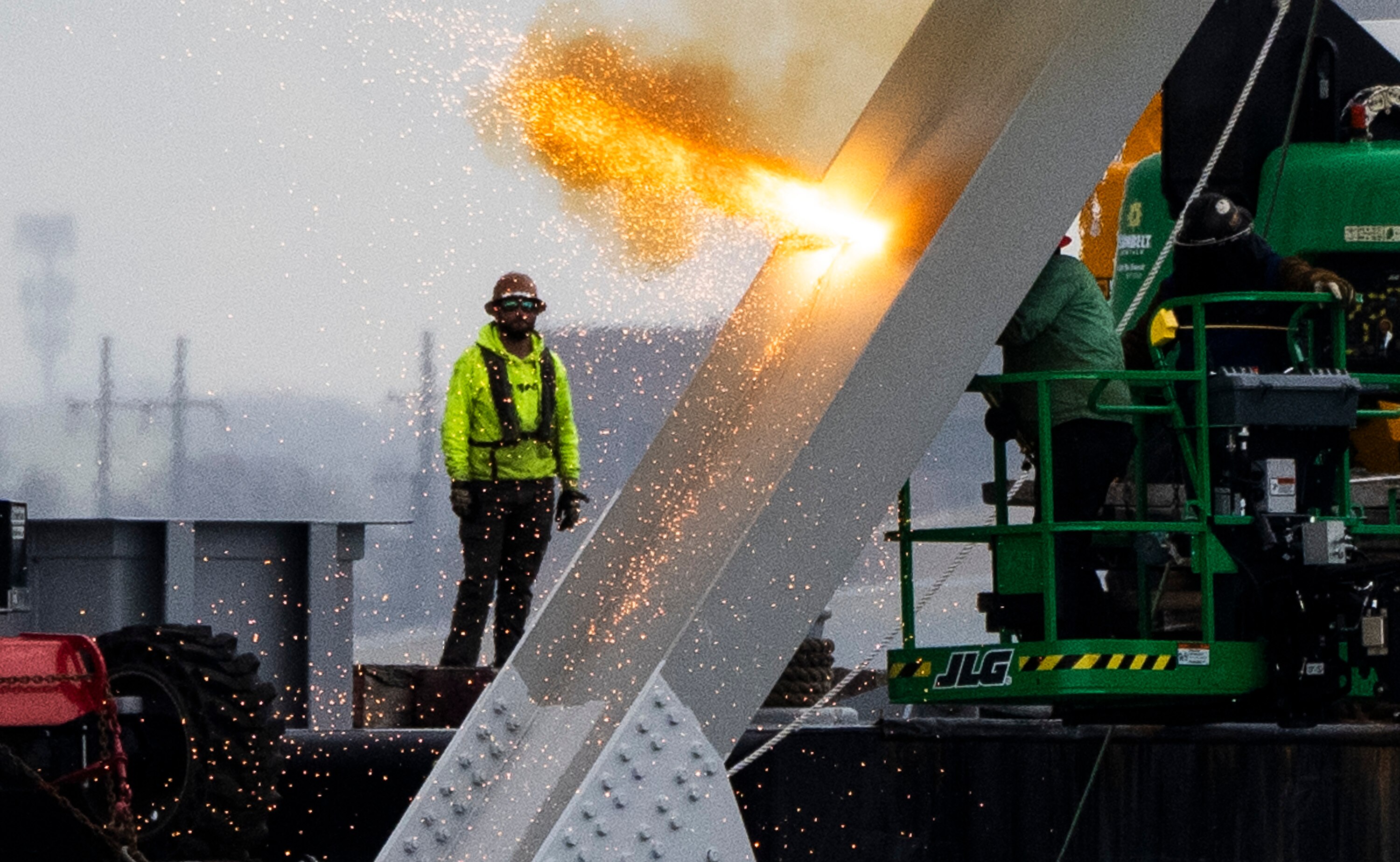 Workers are seen in the beginning stages of dismantling the steel from the frame of the collapsed Key Bridge on April 4, 2024. They are using an exothermic cutting torch.
