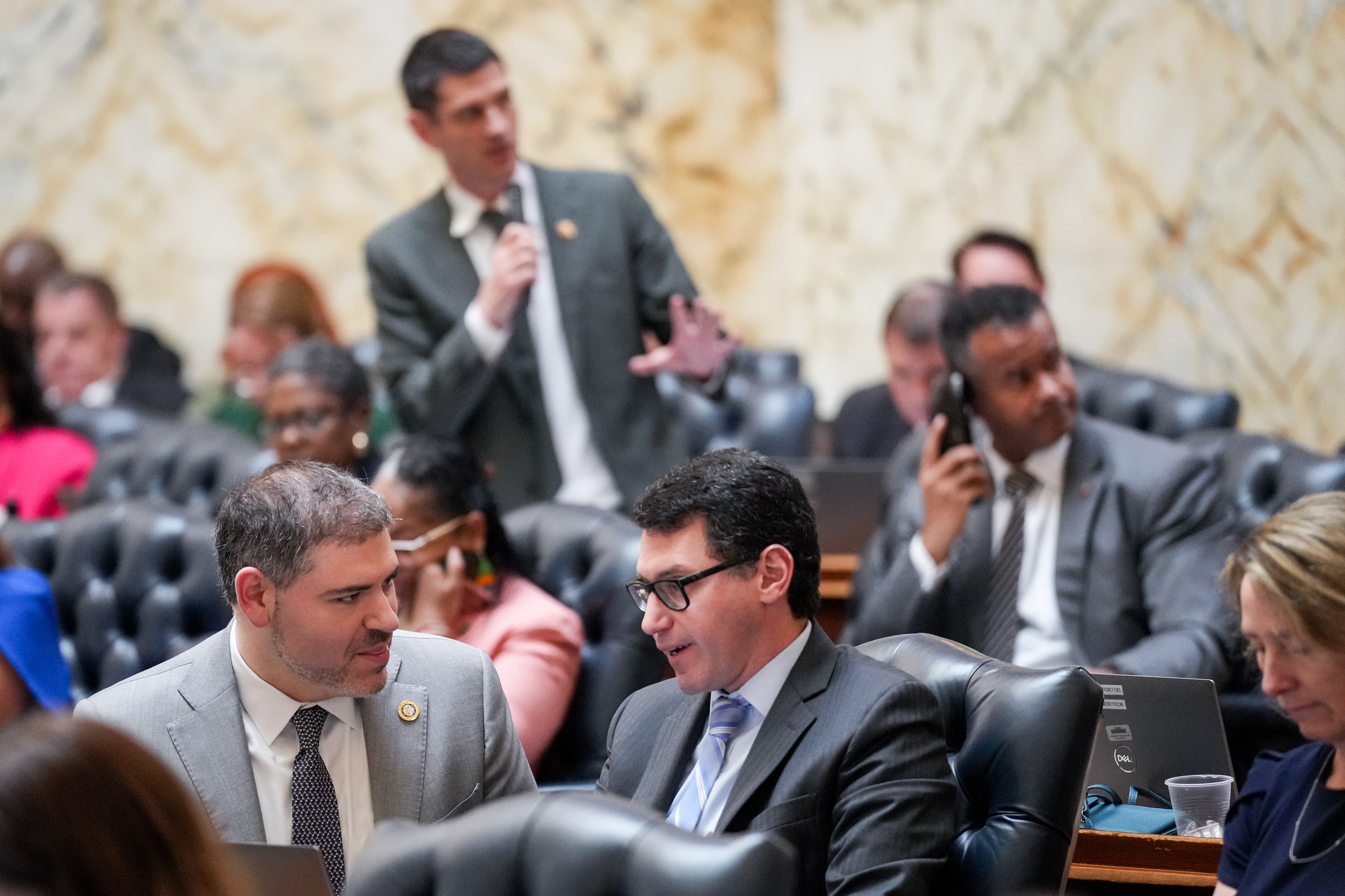 Del. Jared Solomon (left), a Montgomery County Democrat, speaks with Del. Marc Korman, Chair of the Environment and Transportation committee, as other delegates engage in floor debate on “crossover day” in the Maryland State House in Annapolis on March 18, 2024.