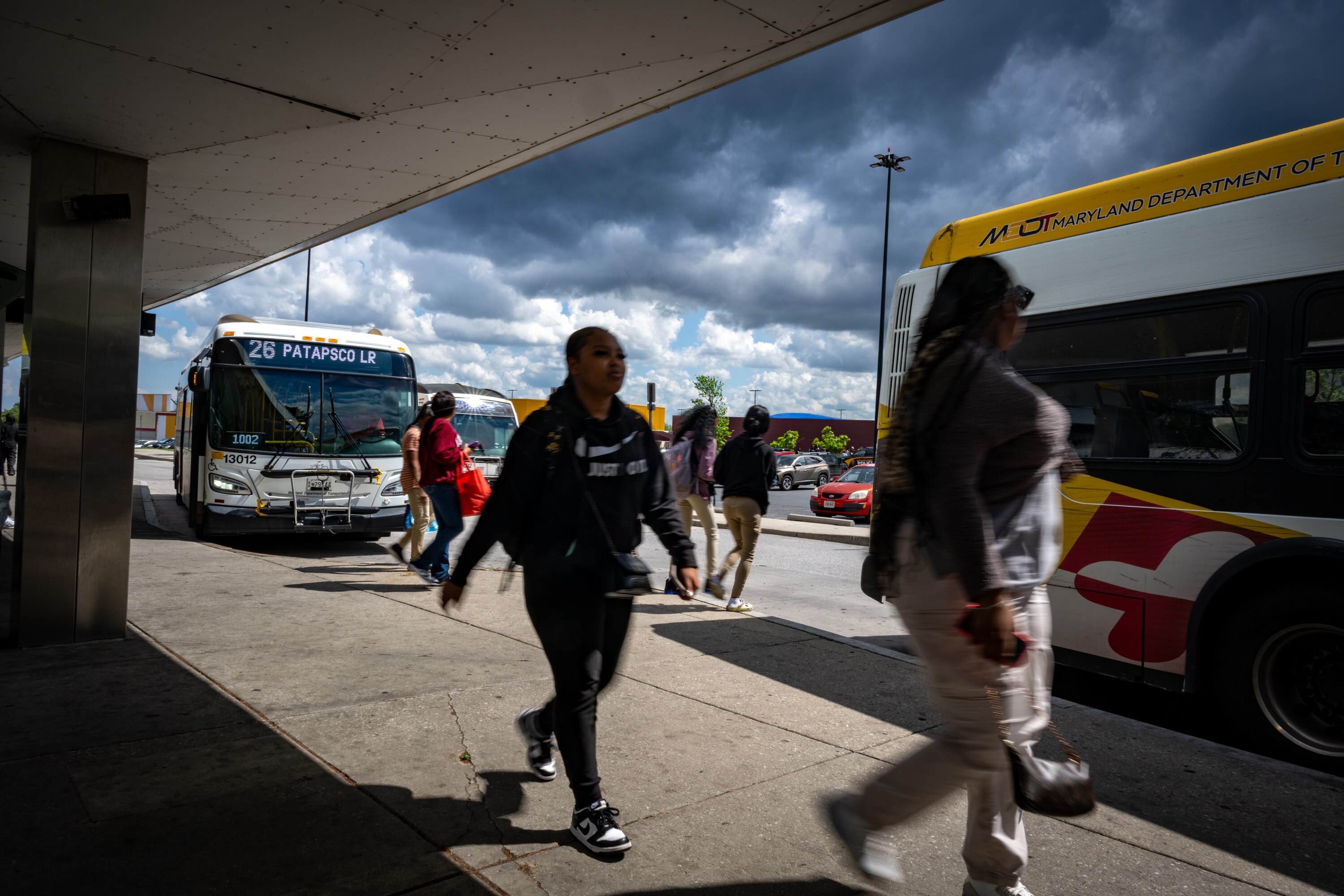 Passengers move between buses at the Mondawmin Transit Hub on May 6, 2025.