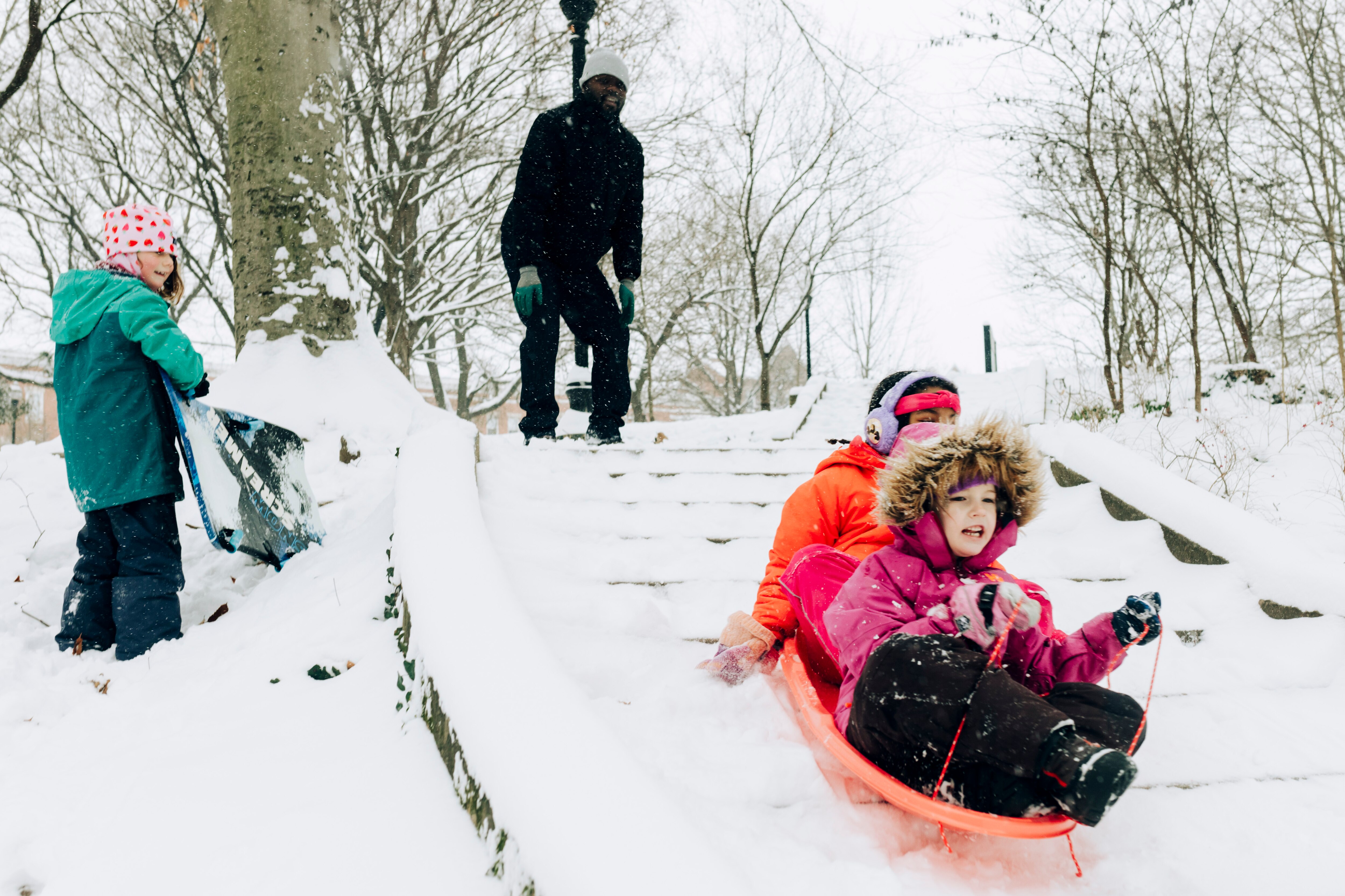 Penny Parish, front, and Joy Duncan sled down the stairs at Wyman Park Dell on the morning after the first lasting snowfall of the winter, in Baltimore, MD on Monday, Jan. 6, 2025.