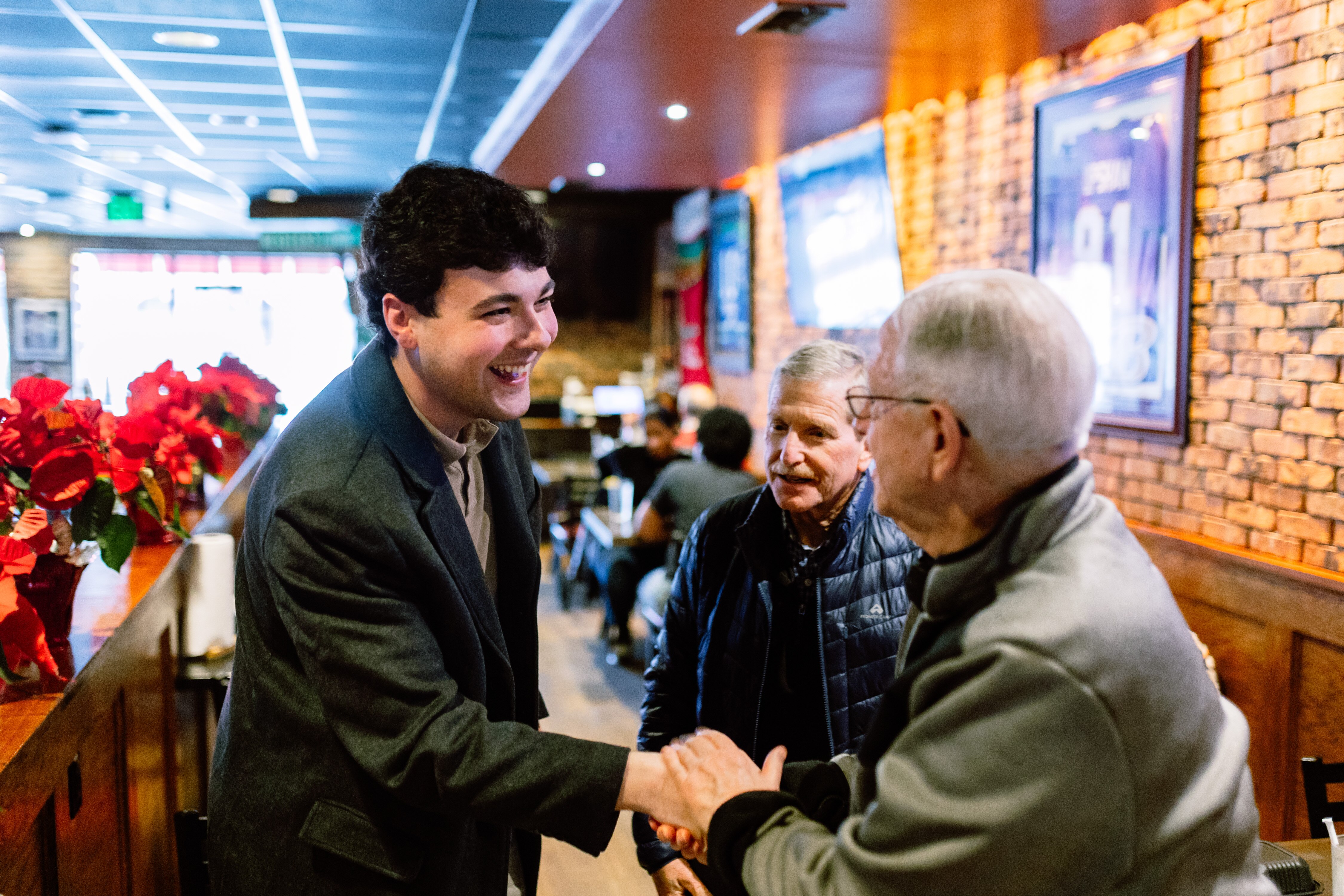 Karson Kamenetz, left, candidate for Baltimore County Council and son of former County Executive Kevin Kamenetz, speaks to Baltimore County residents Alvin Levi, right, and Jeffrey Platt at Jilly’s Bar & Grill in Pikesville.