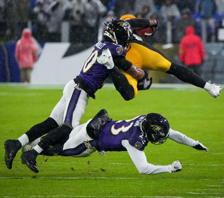 Baltimore Ravens cornerback Arthur Maulet (10) and cornerback Rock Ya-Sin (23) tackle Pittsburgh Steelers running back Najee Harris (22) as he hurdles in a football game at M&T Bank Stadium on Saturday, January 6, 2024.