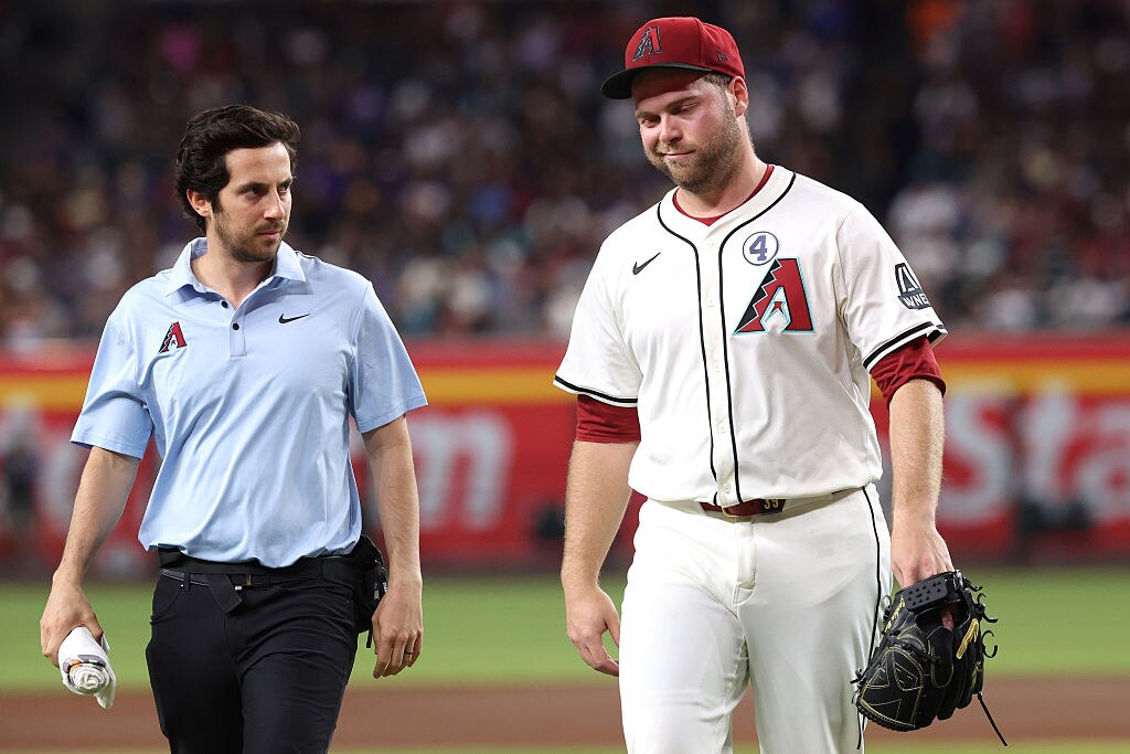 Starting pitcher Corbin Burnes walks off the field with assistant athletic trainer Max Esposito during the fifth inning.