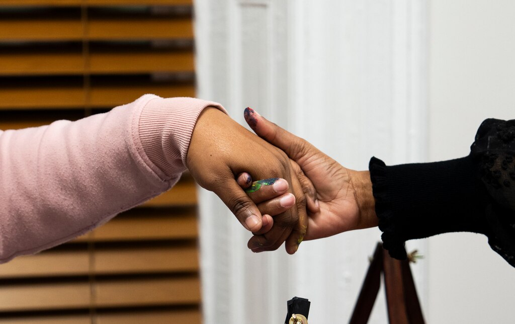 Tameka Lynbrith, mother of Kylis Fagbemi, who was killed in the Brooklyn Homes shooting in July, holds hands during prayer with Donna Bruce at Sip and Paint night on December 16, 2023.