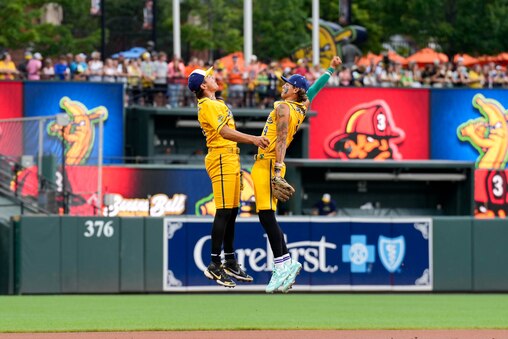 Savannah Bananas players jump together in the outfield during a Banana Ball game against The Firefighters at Oriole Park at Camden Yards in Baltimore, Md. on Friday, August 1, 2025. It’s the first of two games to be played at Camden Yards this weekend.