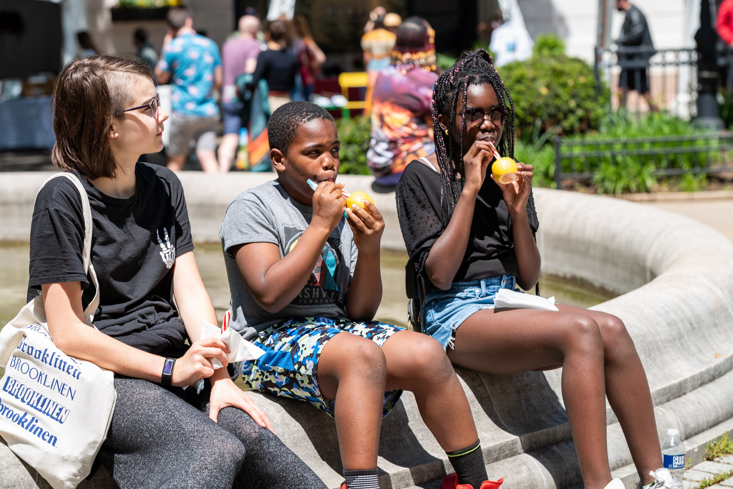 From left, Ella, Brooks and Cora Emhoff enjoy lemon sticks at the 2023 Flower Mart.