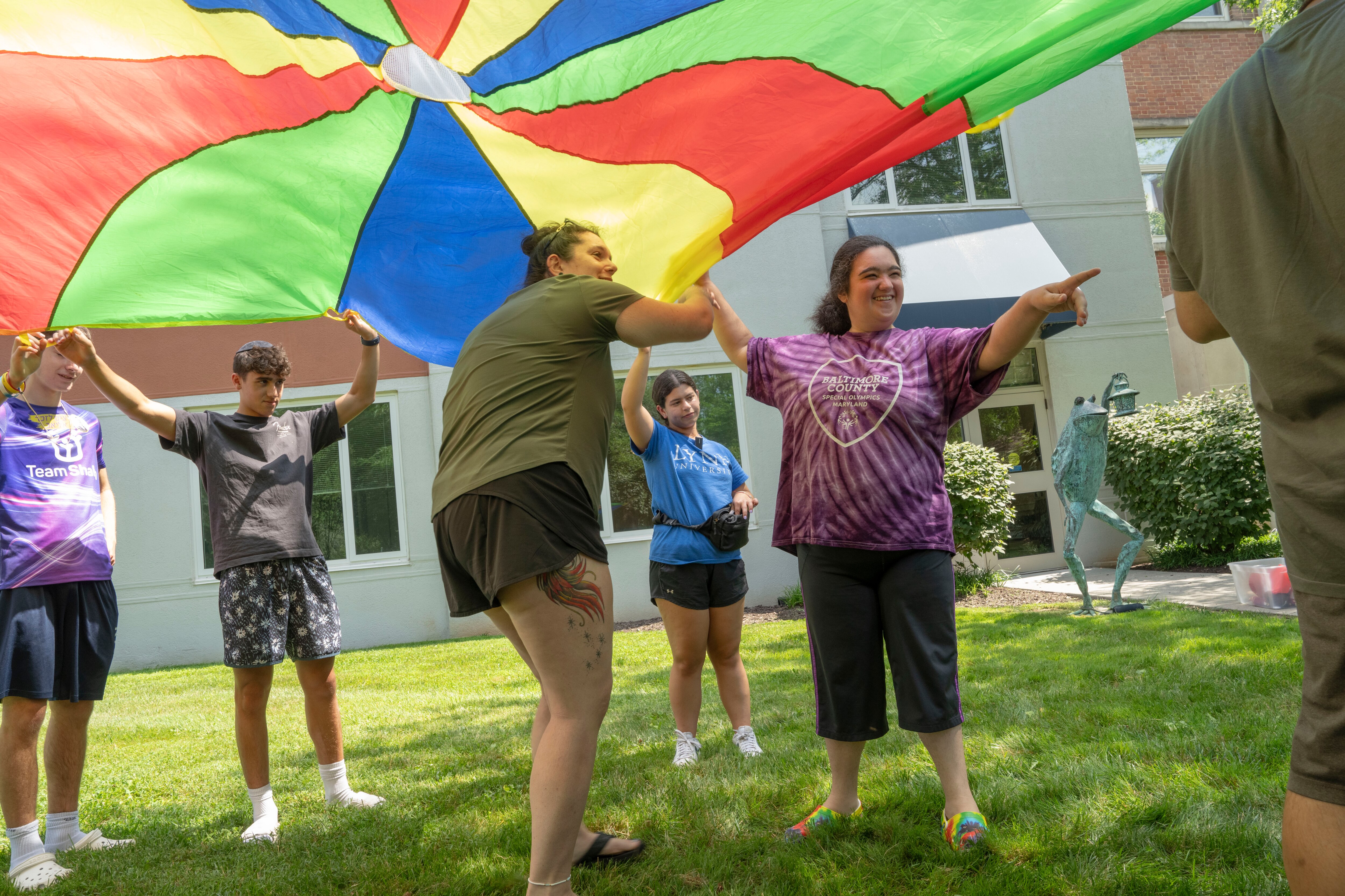 Jessica Bly, center, helps camp attendees dance under a parachute during the Spark Summer Program.