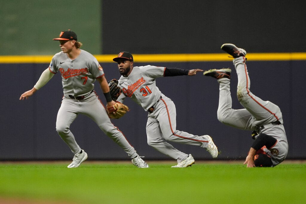 Baltimore Orioles' Jackson Holliday (7), Cedric Mullins (31), and Ramón Laureano, right, are unable to reach a fly ball during the fourth inning of a baseball game against the Milwaukee Brewers, Tuesday, May 20, 2025, in Milwaukee.