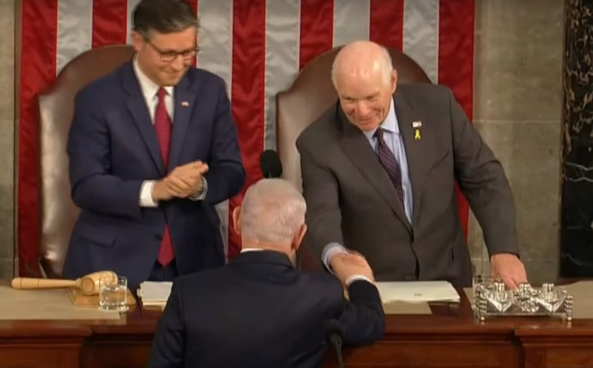 U.S. Sen. Ben Cardin reaches down to shake the hand of Israeli Prime Minister Benjamin Netanyahu Wednesday at the start of a joint session of Congress. Cardin shared the podium with House Speaker Mike Johnson.