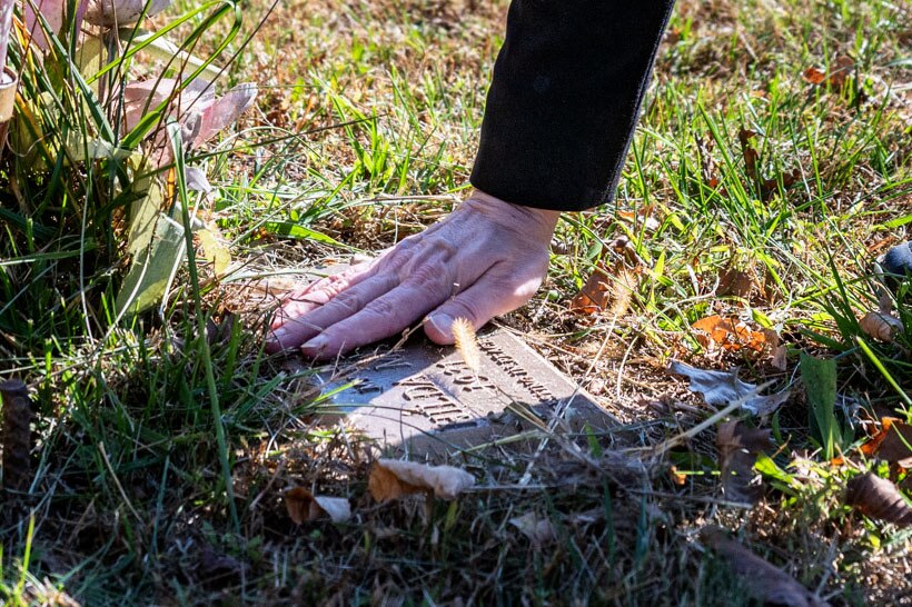 Candy Warden brushes leaves and grass off the grave marker for Hilda Maria Gray, one of several people buried alongside pets in the Rosa Bonheur Memorial Park in Elkridge.