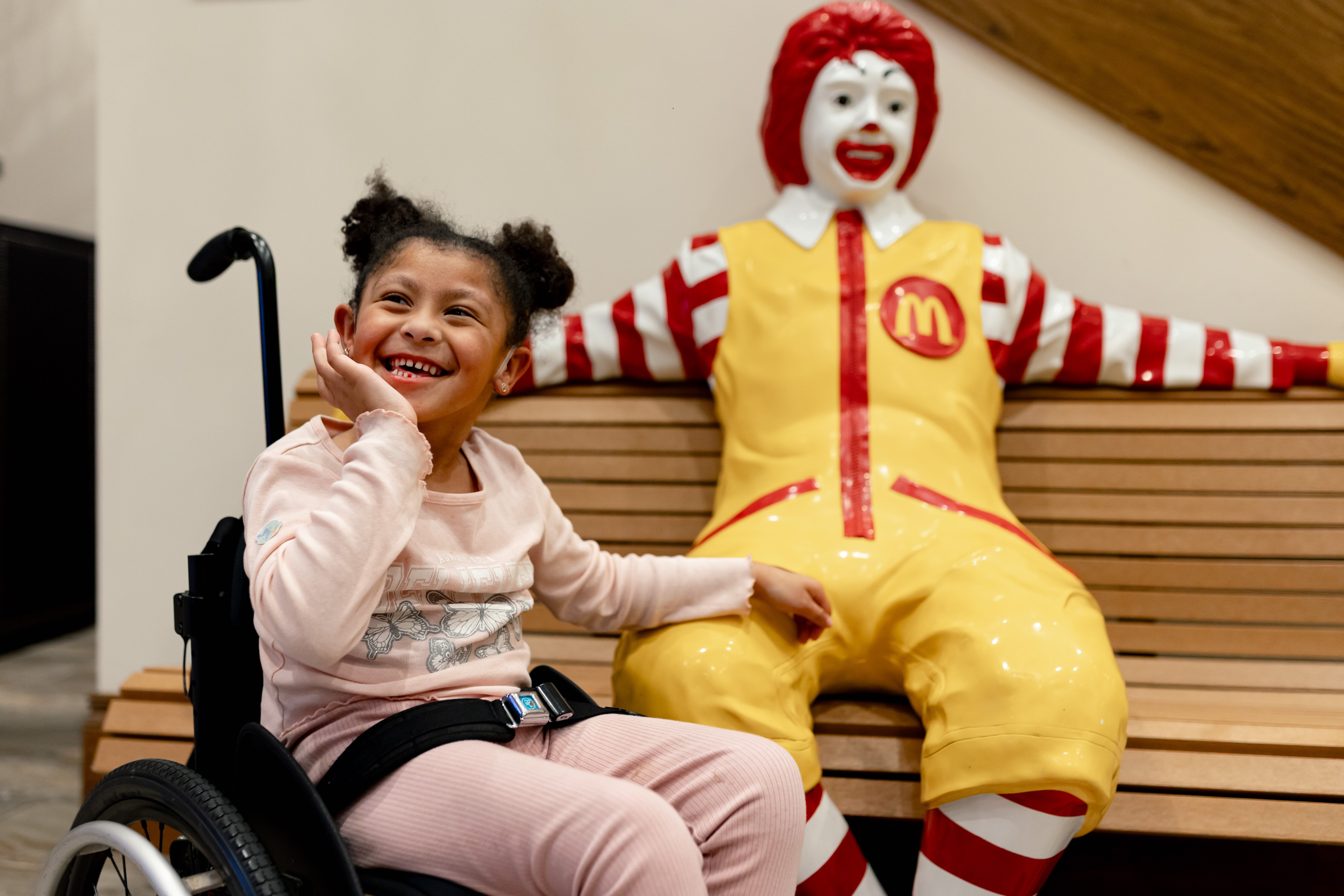 Isla Saccente, who is being treated for cerebral palsy, poses with a Ronald McDonald statue after dinner at the Ronald McDonald House Charities Maryland building in Baltimore, MD on Thursday, Oct. 16, 2025.