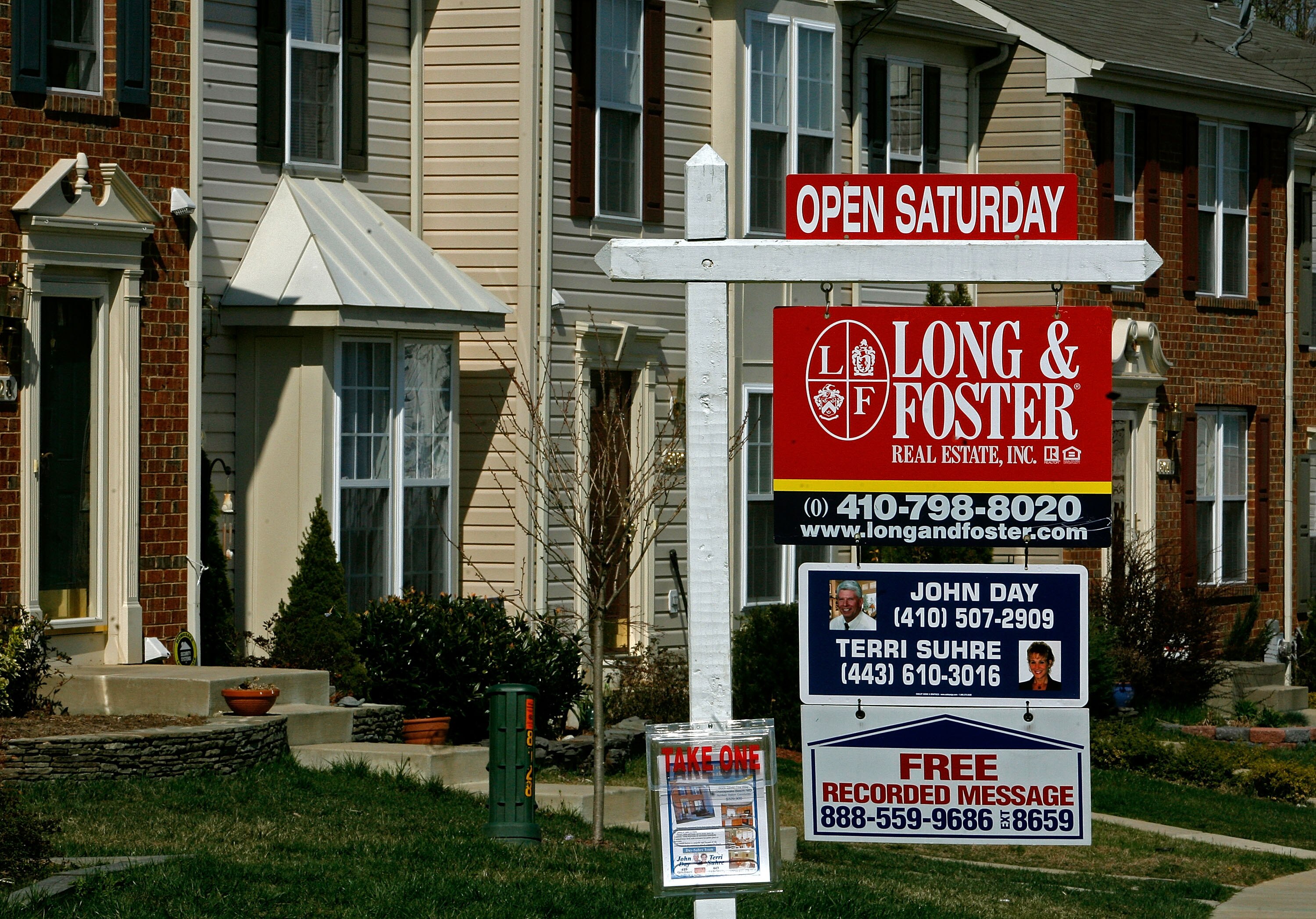 A for sale sign stands in front of a row of townhouses in Chesapeake Beach, Maryland.