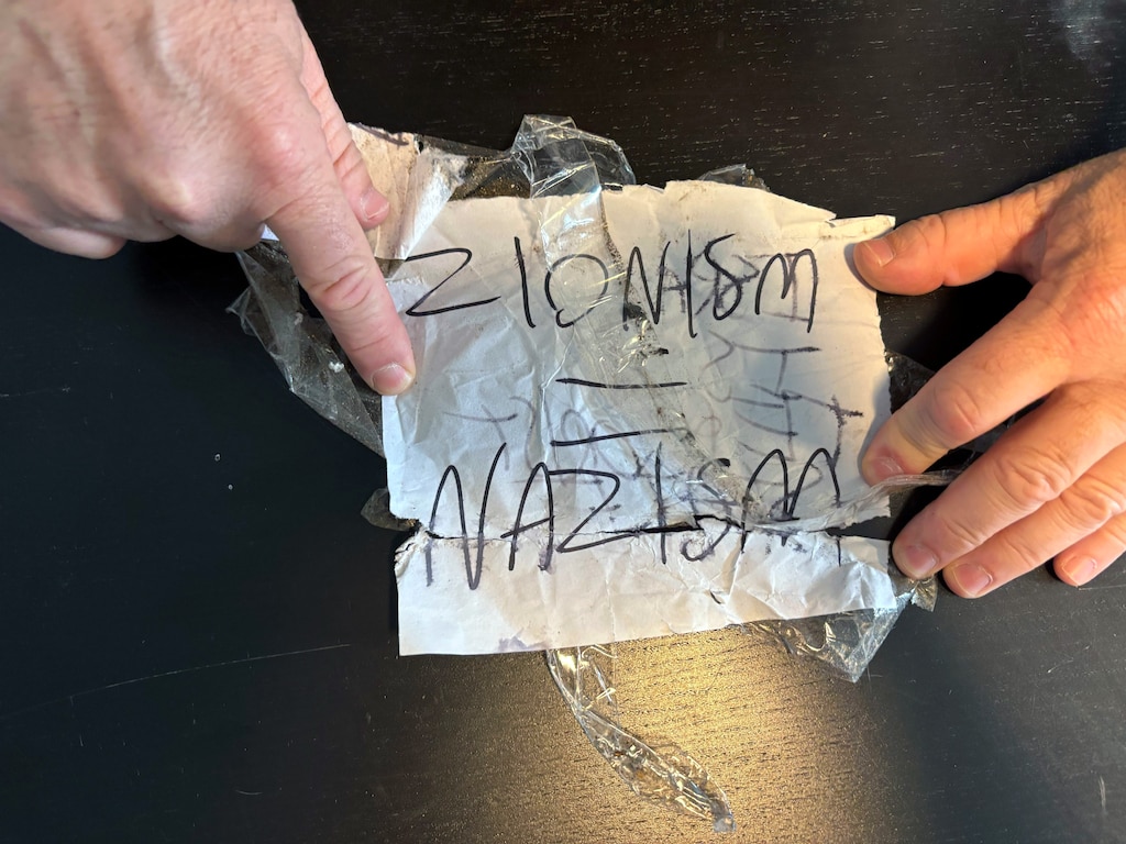 Azi Rosenblum displays a note, which reads “Zionism = Nazism”, that was wrapped around a brick thrown through his window earlier this year.