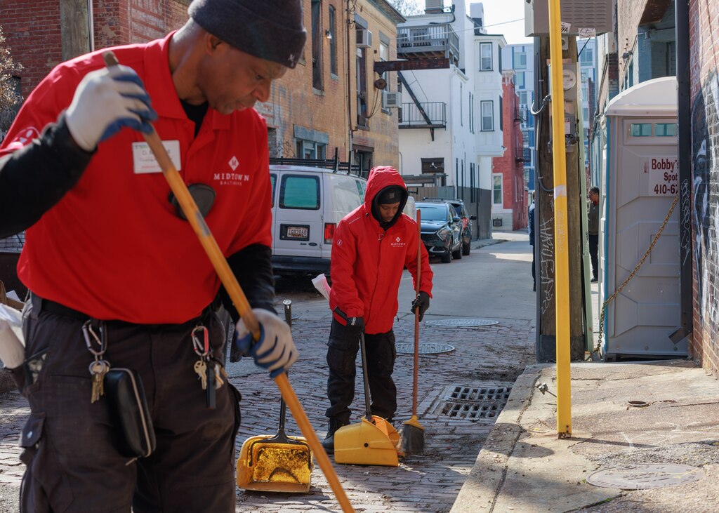 Dwayne Marshall (left) and Jamal Burnett, both Midtown Community Benefits District crew members, pick up trash left in an alleyway in the Station North neighborhood of Baltimore, MD on March 4, 2025.
